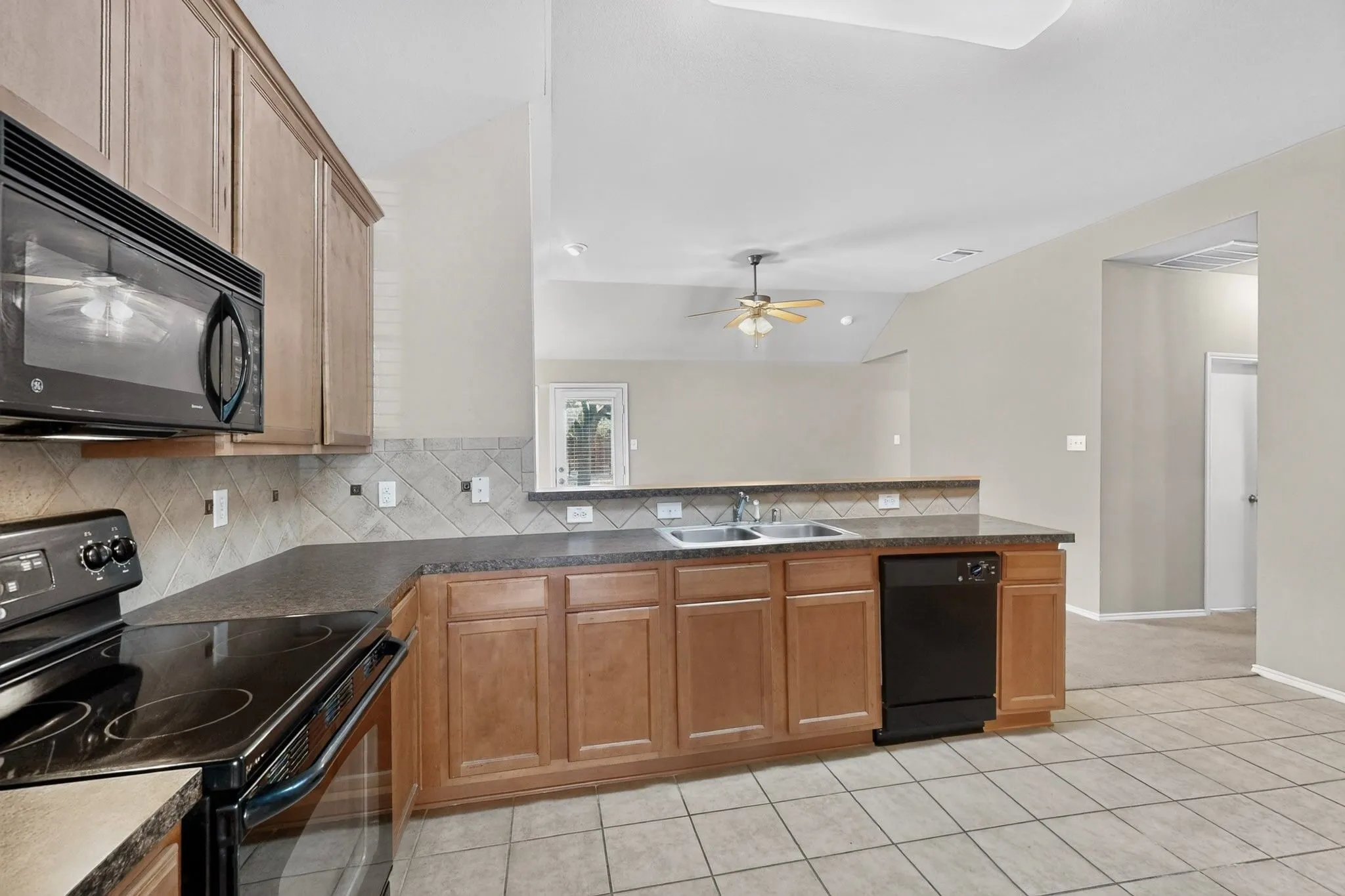 Kitchen featuring wood-finish cabinetry, built-in microwave, electric range, dishwasher, and a dual basin sink