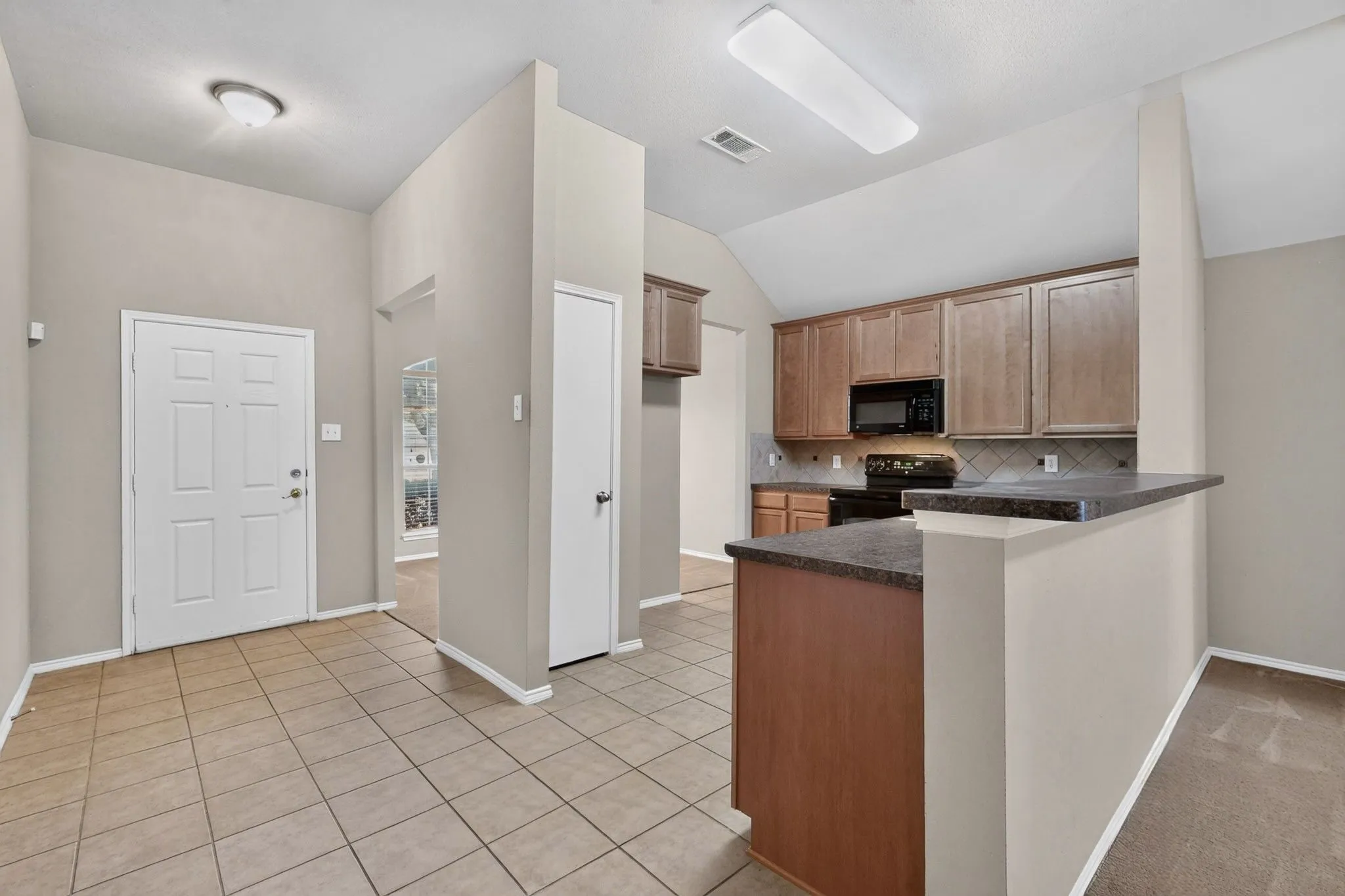 Tile flooring in the entry and kitchen with a vaulted ceiling