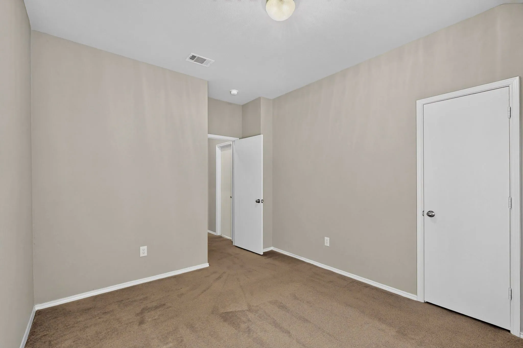 Neutral wall finishes, carpeted flooring, and a flush mount ceiling light