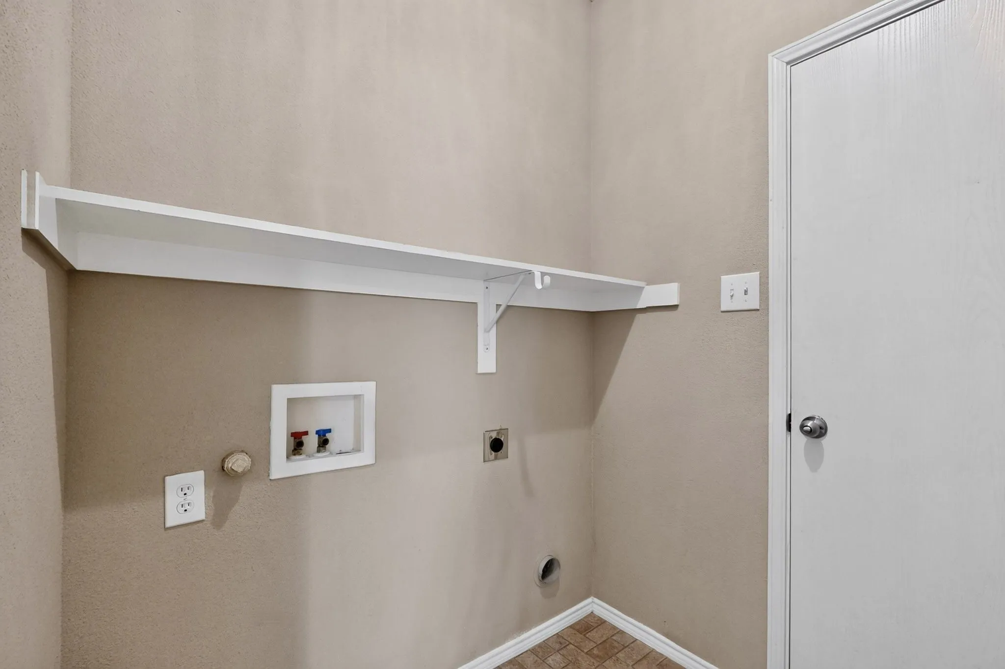 White built-in shelving, utility hookups, and a privacy door