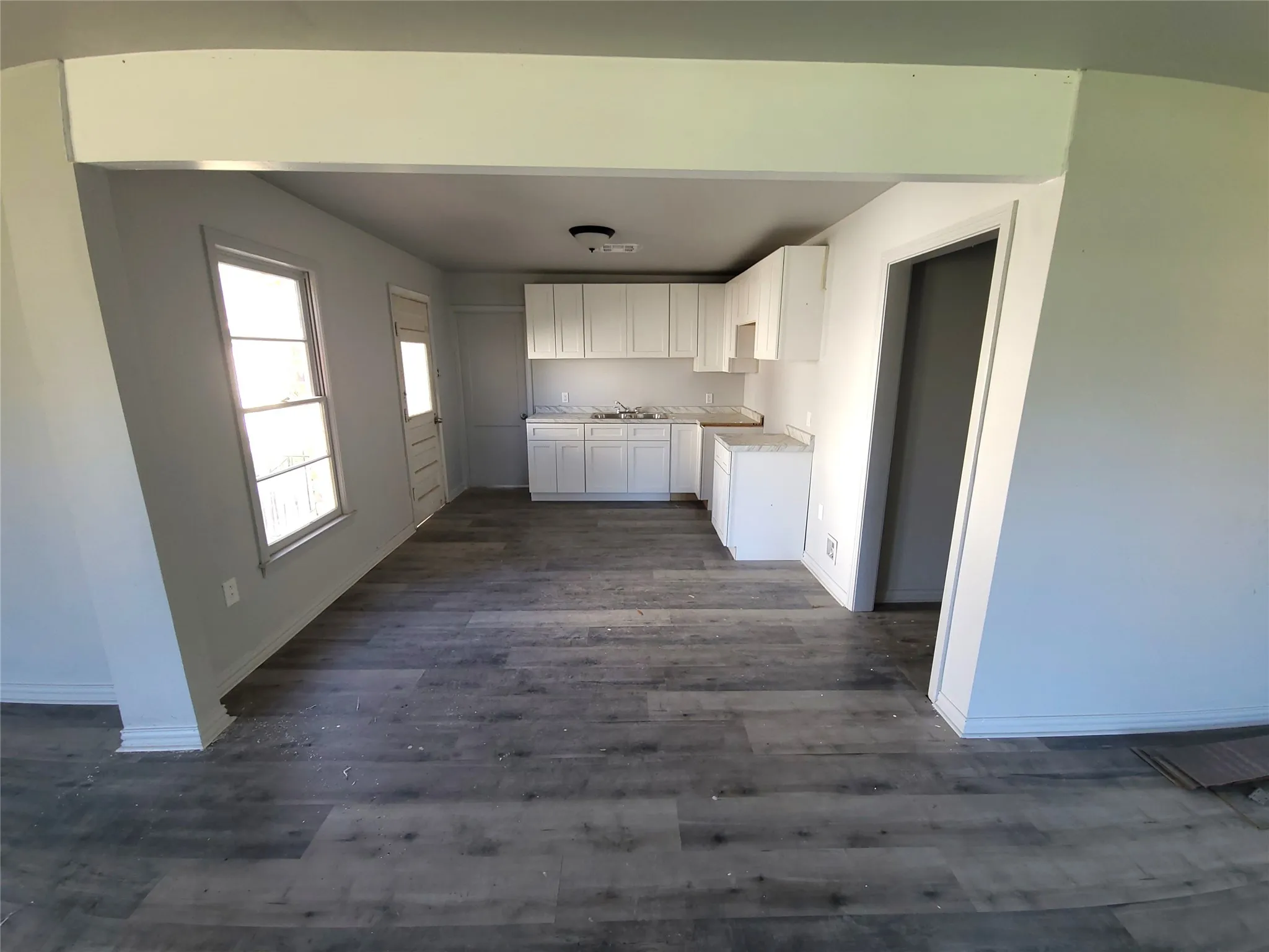 View into Open Concept Kitchen with white cabinetry, light countertops, and dark wood finished floors
