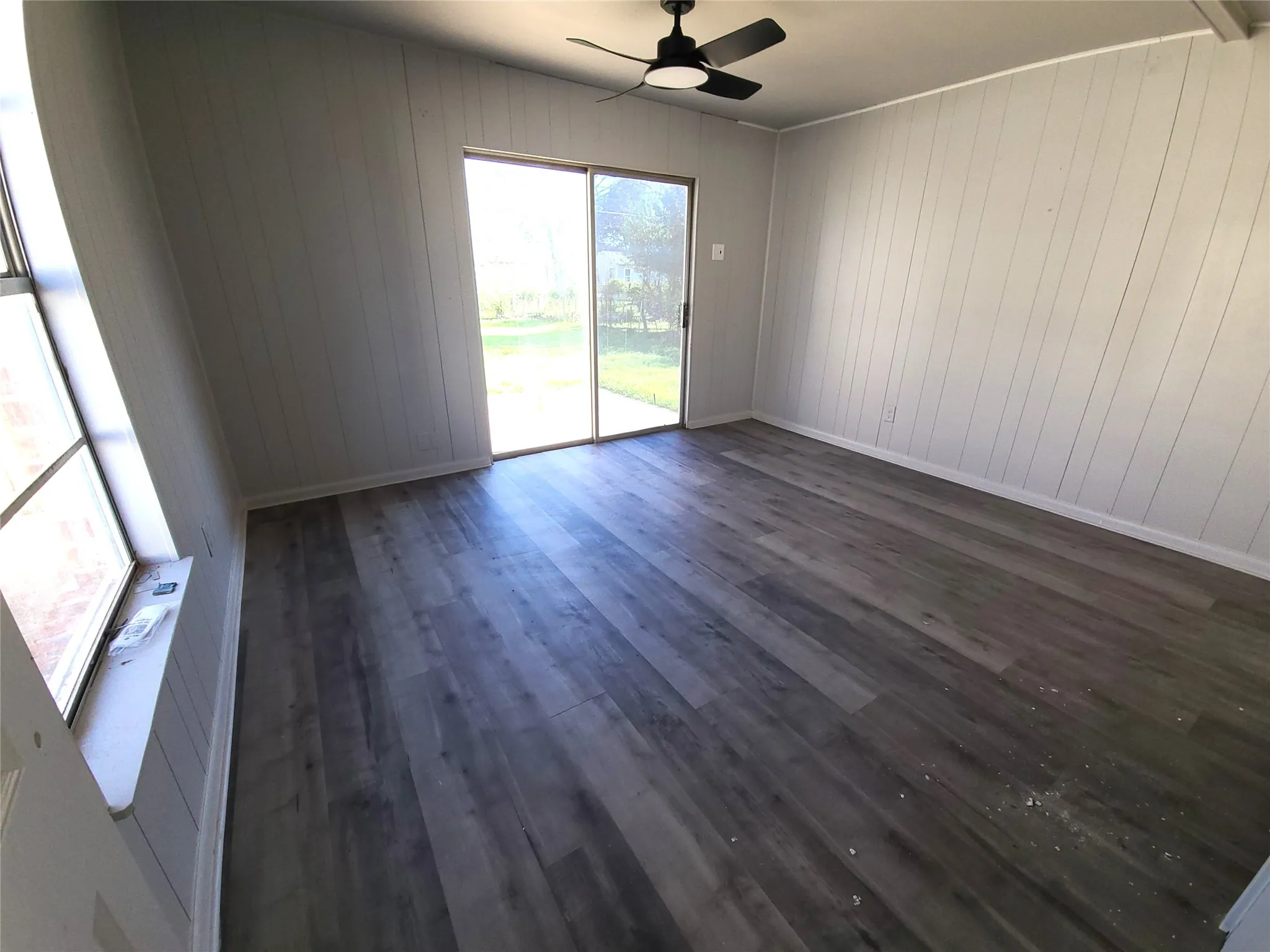 Primary Bedroom with dark wood finished floors, a ceiling fan, and wooden walls