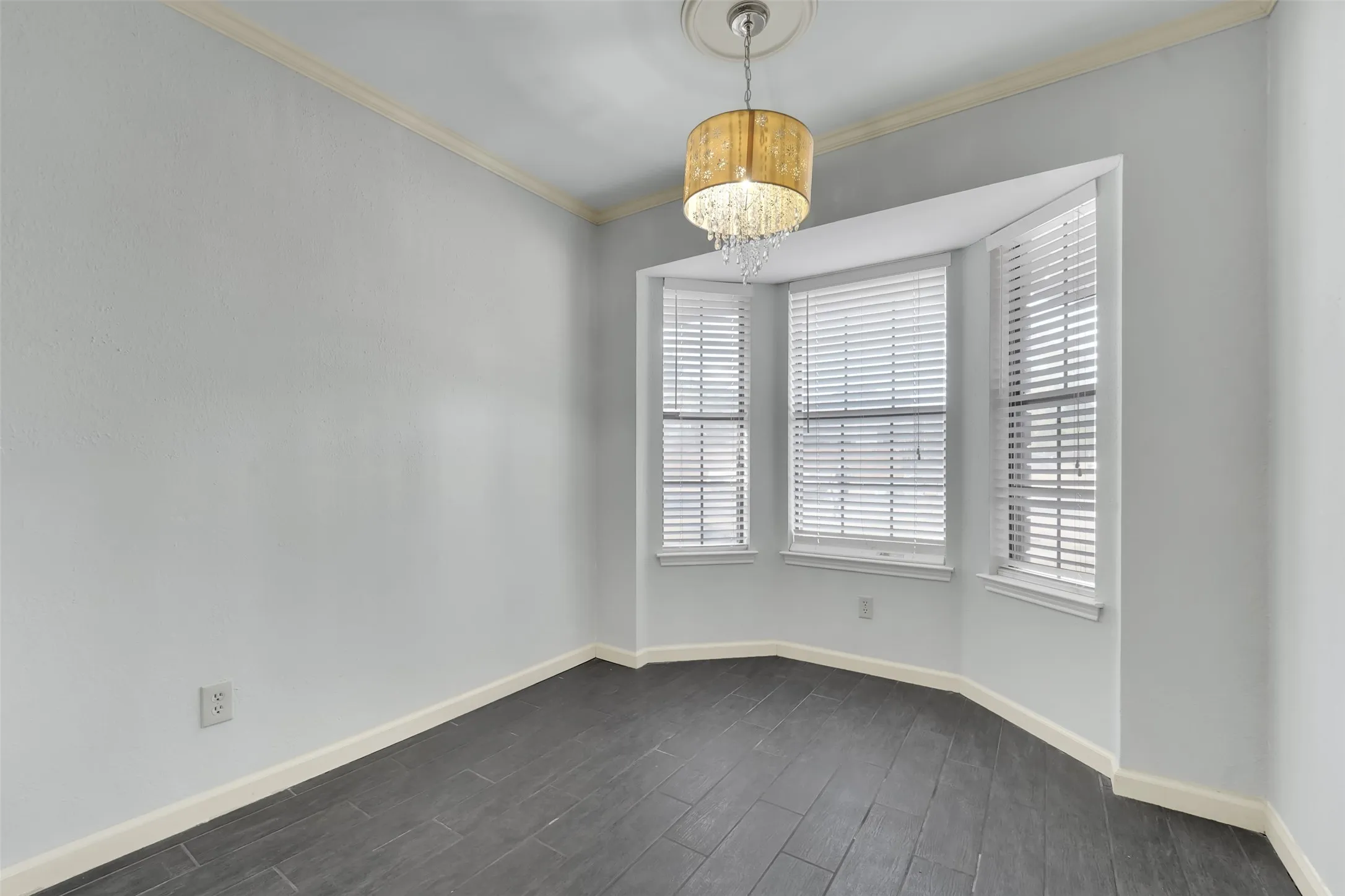 Bay window with multiple windows, crown molding, a decorative chandelier, and dark wood-finish flooring