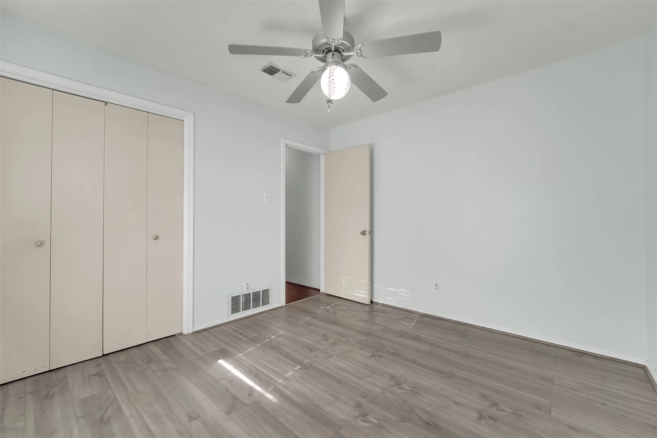 Wood-finish flooring, ceiling fan with integrated lighting, and neutral wall color