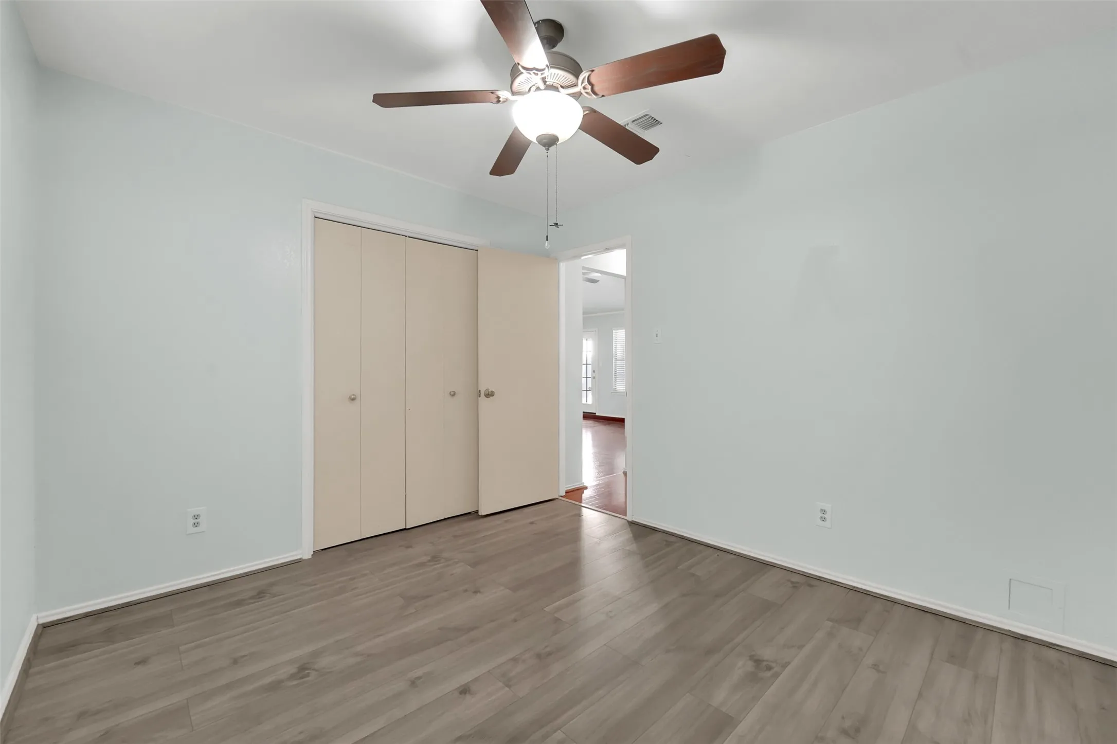 Wood-finish flooring, ceiling fan with integrated lighting, and bi-fold closet doors