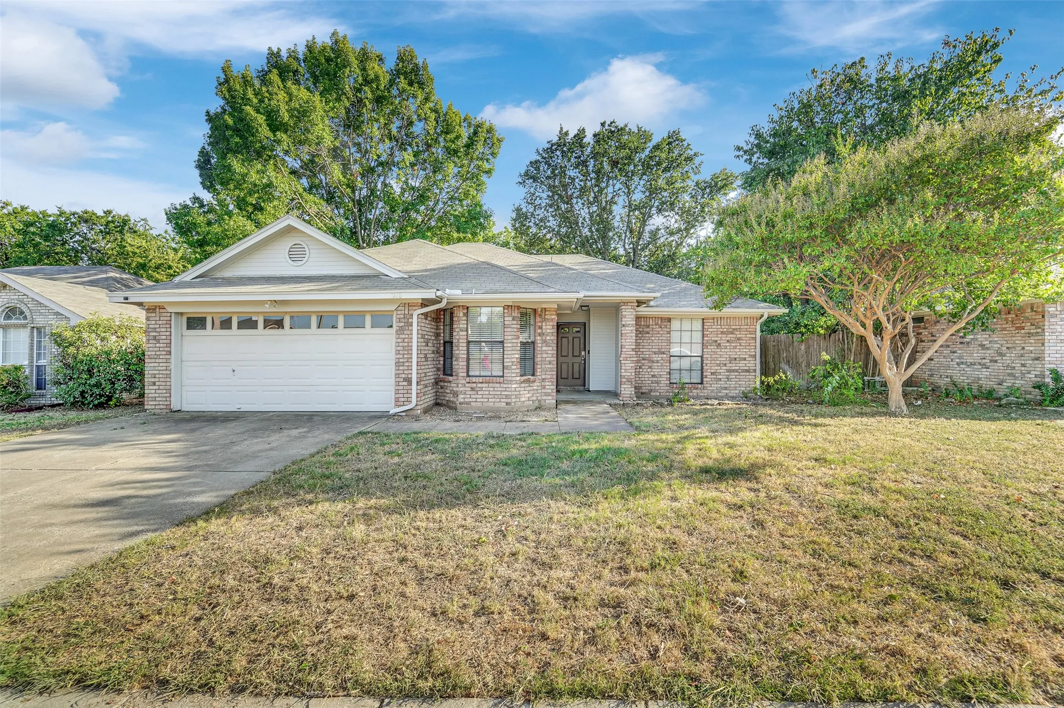 Brick exterior with an attached garage, paved driveway, and covered entry