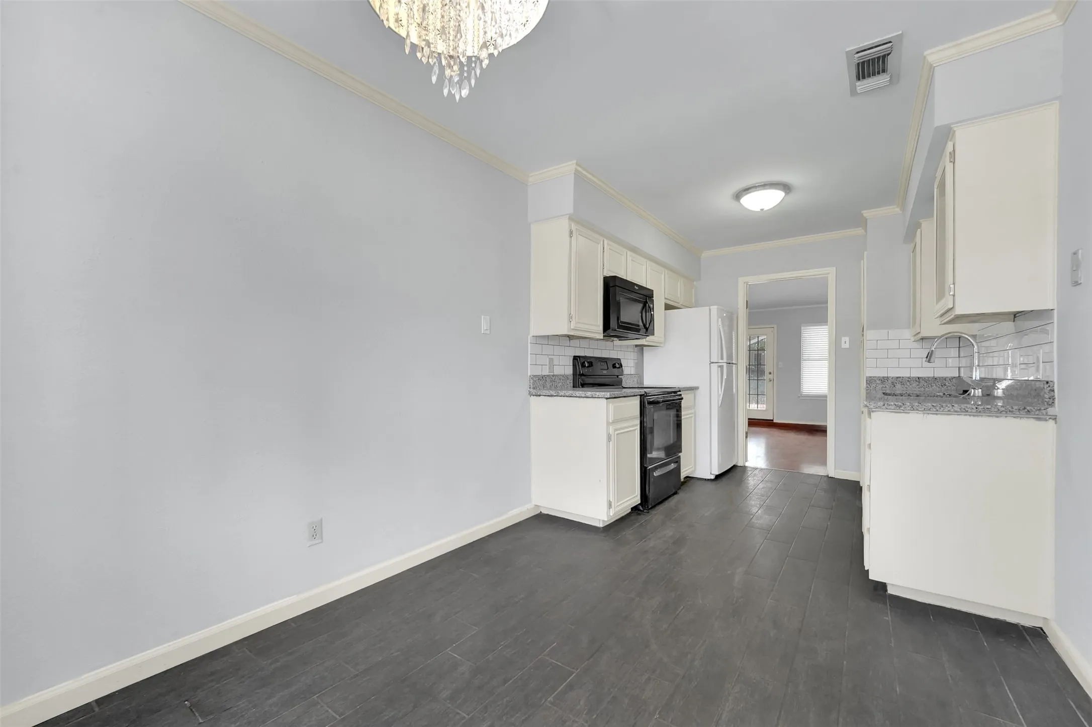 Kitchen featuring white cabinetry, gray countertops, white subway tile backsplash, and dark wood-finish flooring
