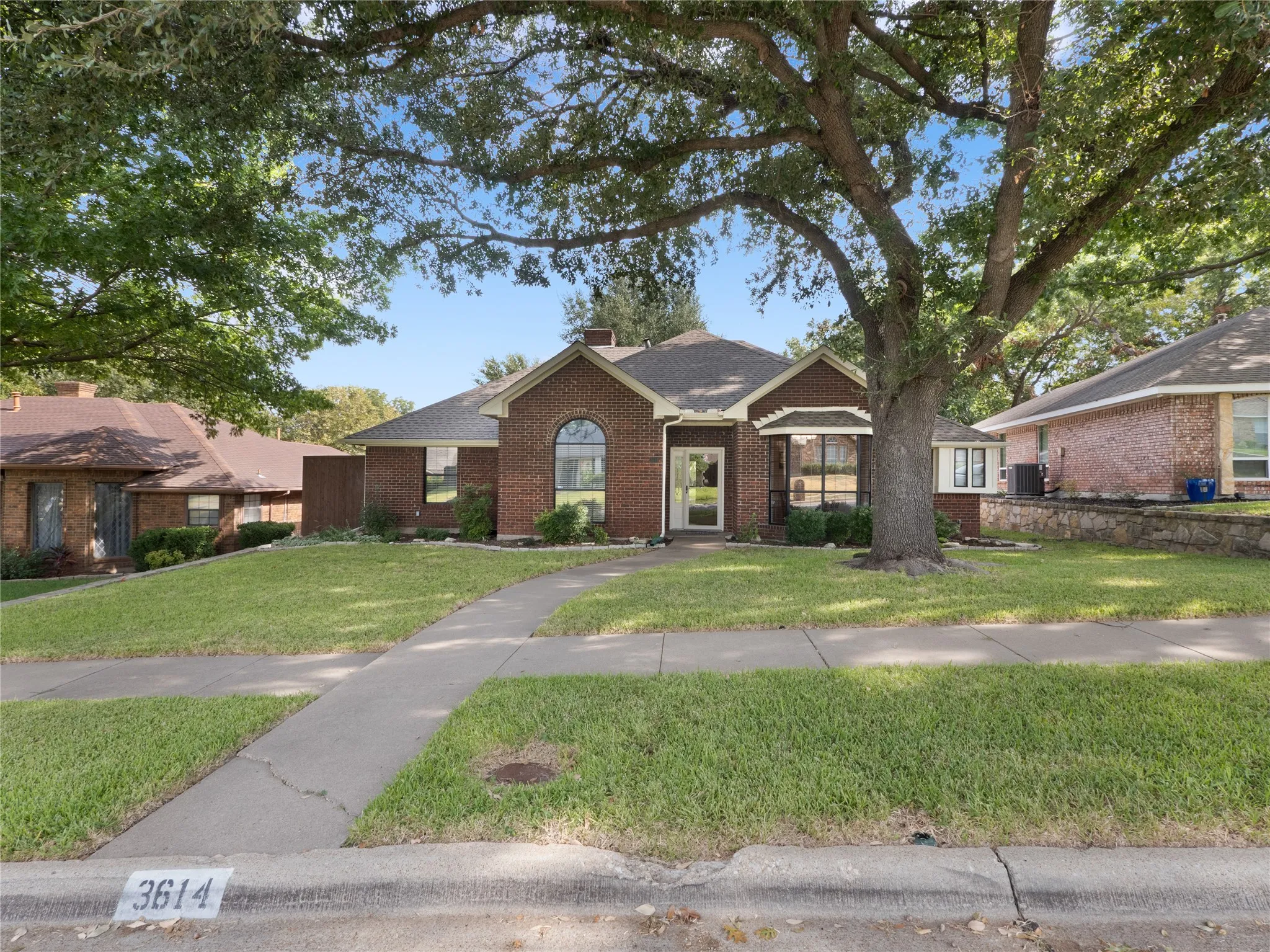Brick exterior with a stone retaining wall and mature tree