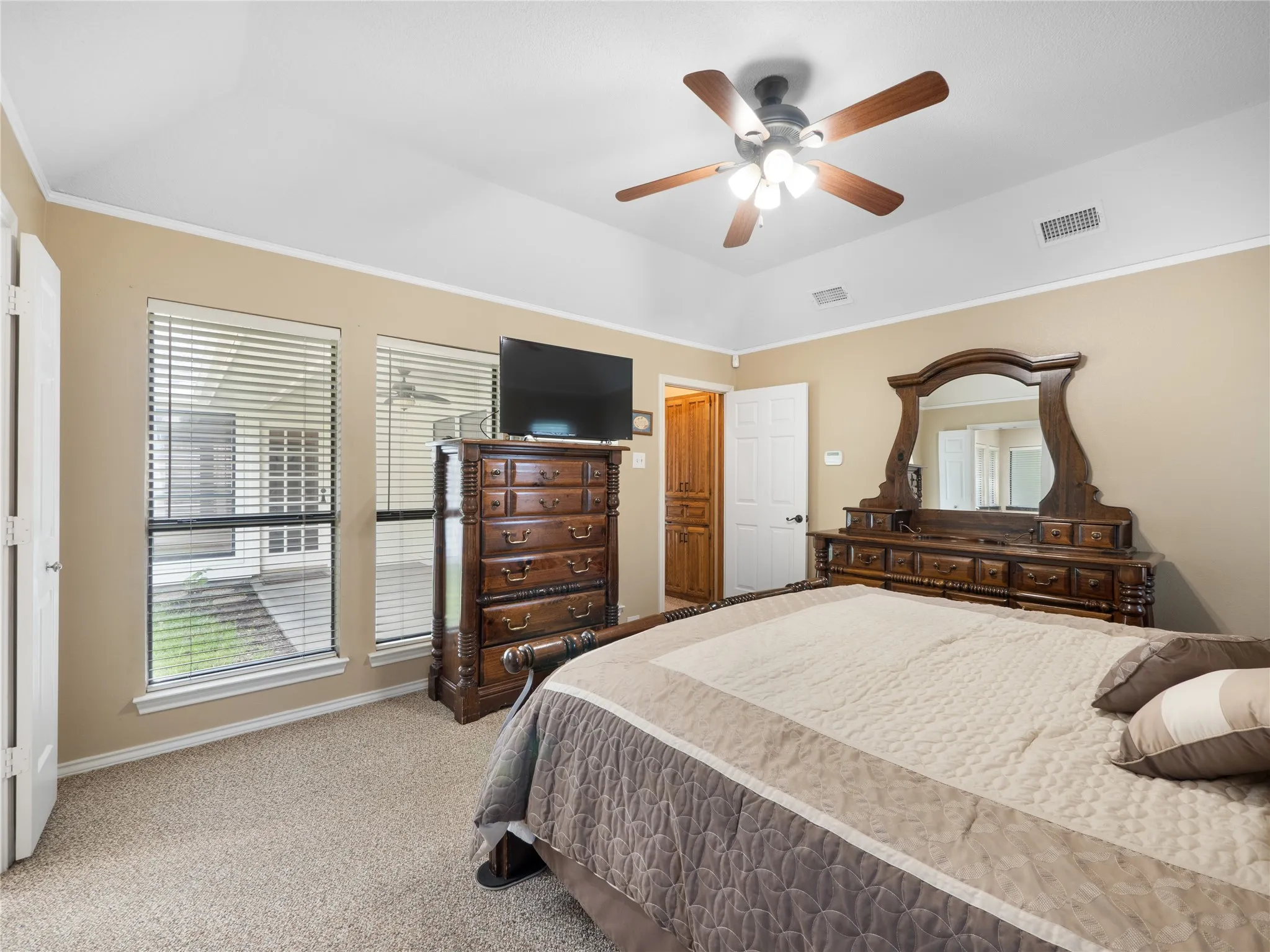 Primary bedroom featuring textured carpeting, neutral wall color, window with horizontal blinds, and a ceiling fan with light fixture
