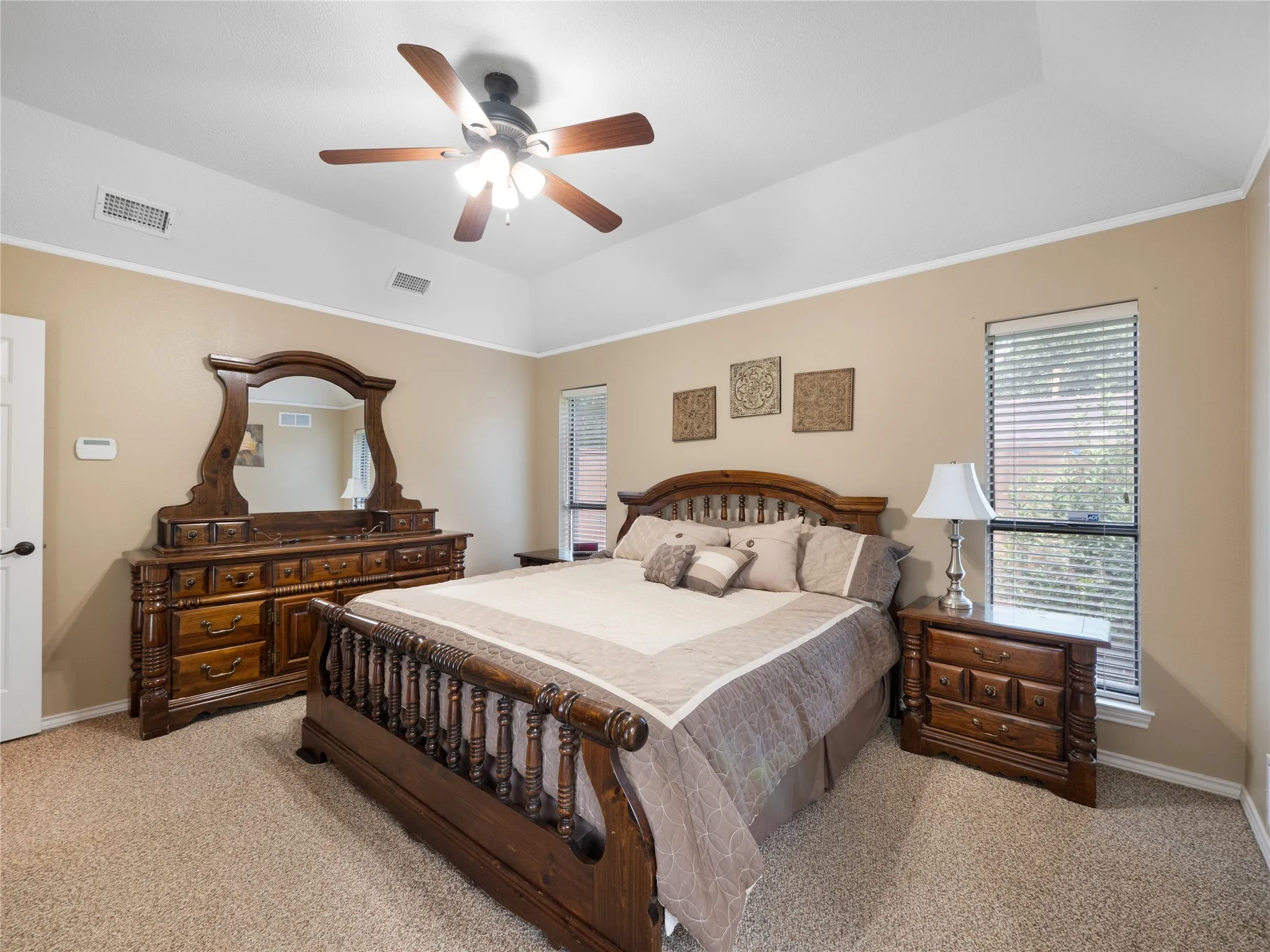 Primary bedroom with vaulted ceiling, ceiling fan with integrated lighting, arched window with blinds, panel door, and carpet flooring