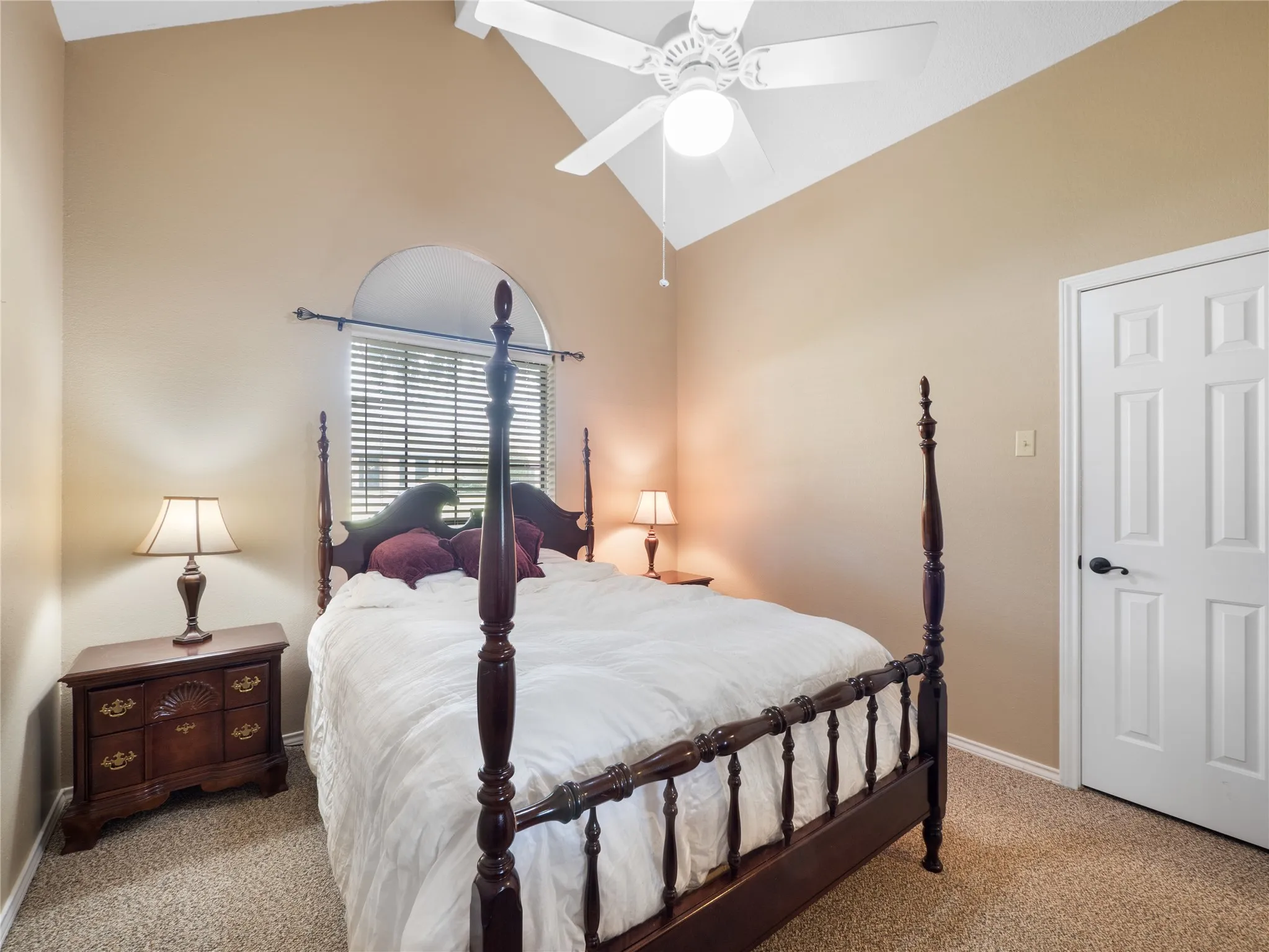 Secondary bedroom with tray ceiling with crown molding, ceiling fan with light fixture, two windows with blinds, and carpeted flooring