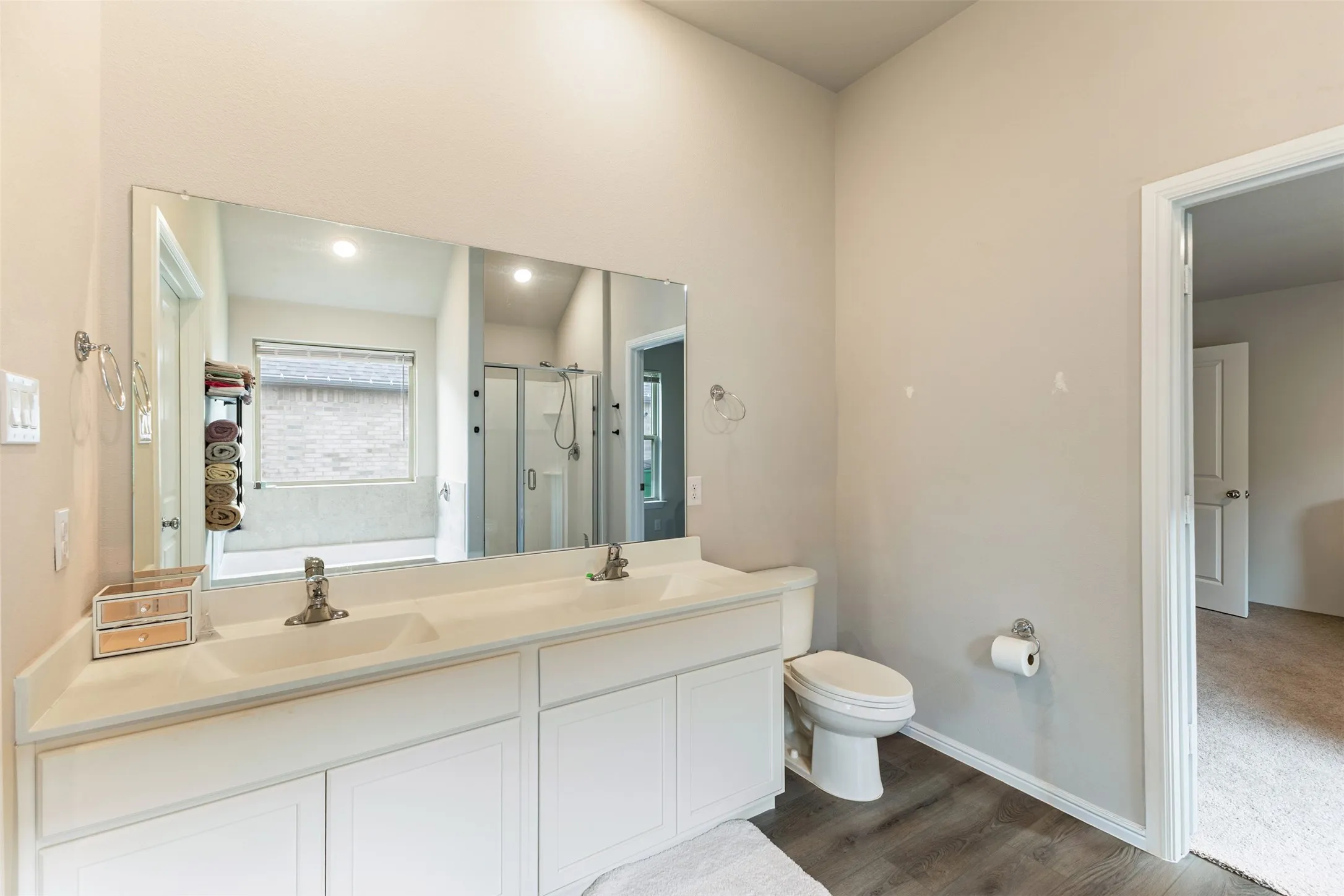 Bathroom featuring a garden tub, a shower stall, double vanity, and dark wood-style flooring