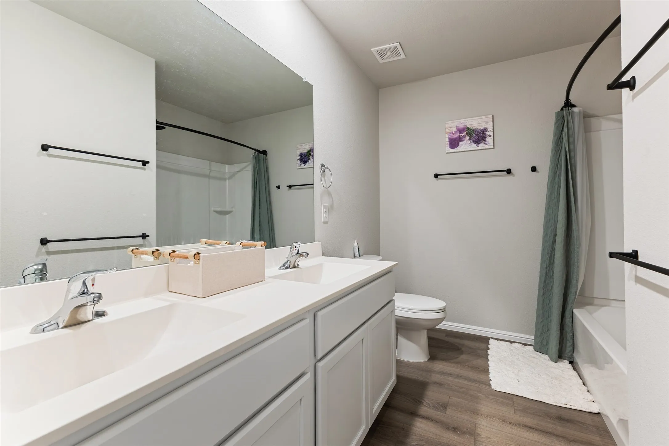 Bathroom featuring dark wood-type flooring, double vanity, and shower / bath combination with curtain