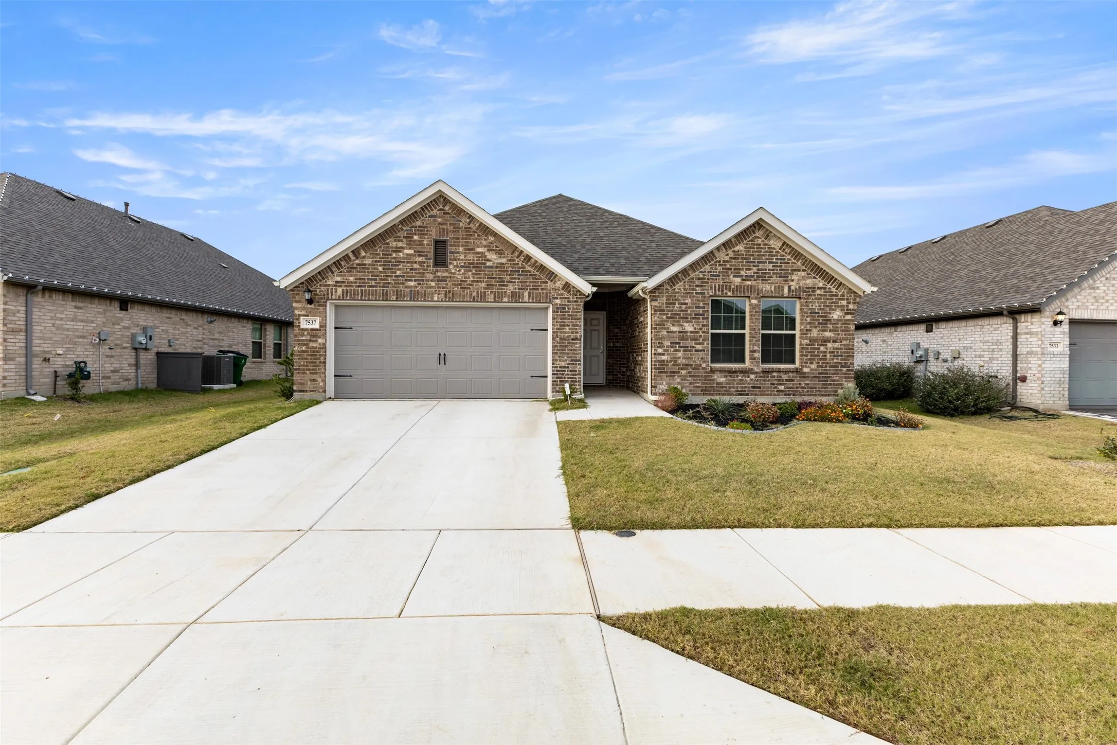 View of front of house with driveway, a front lawn, brick siding, an attached garage, and roof with shingles