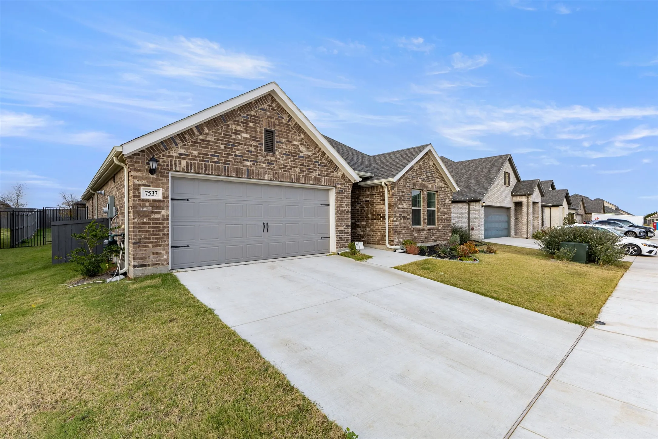 View of front facade with concrete driveway, brick siding, an attached garage, and roof with shingles