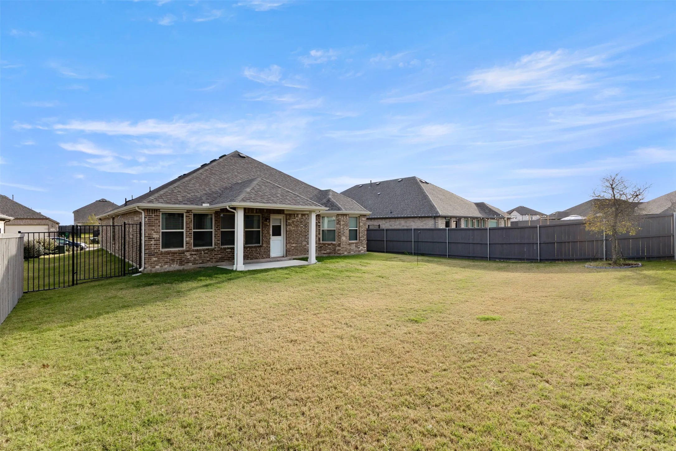 Back of house featuring a patio, a fenced backyard, brick siding, and roof with shingles