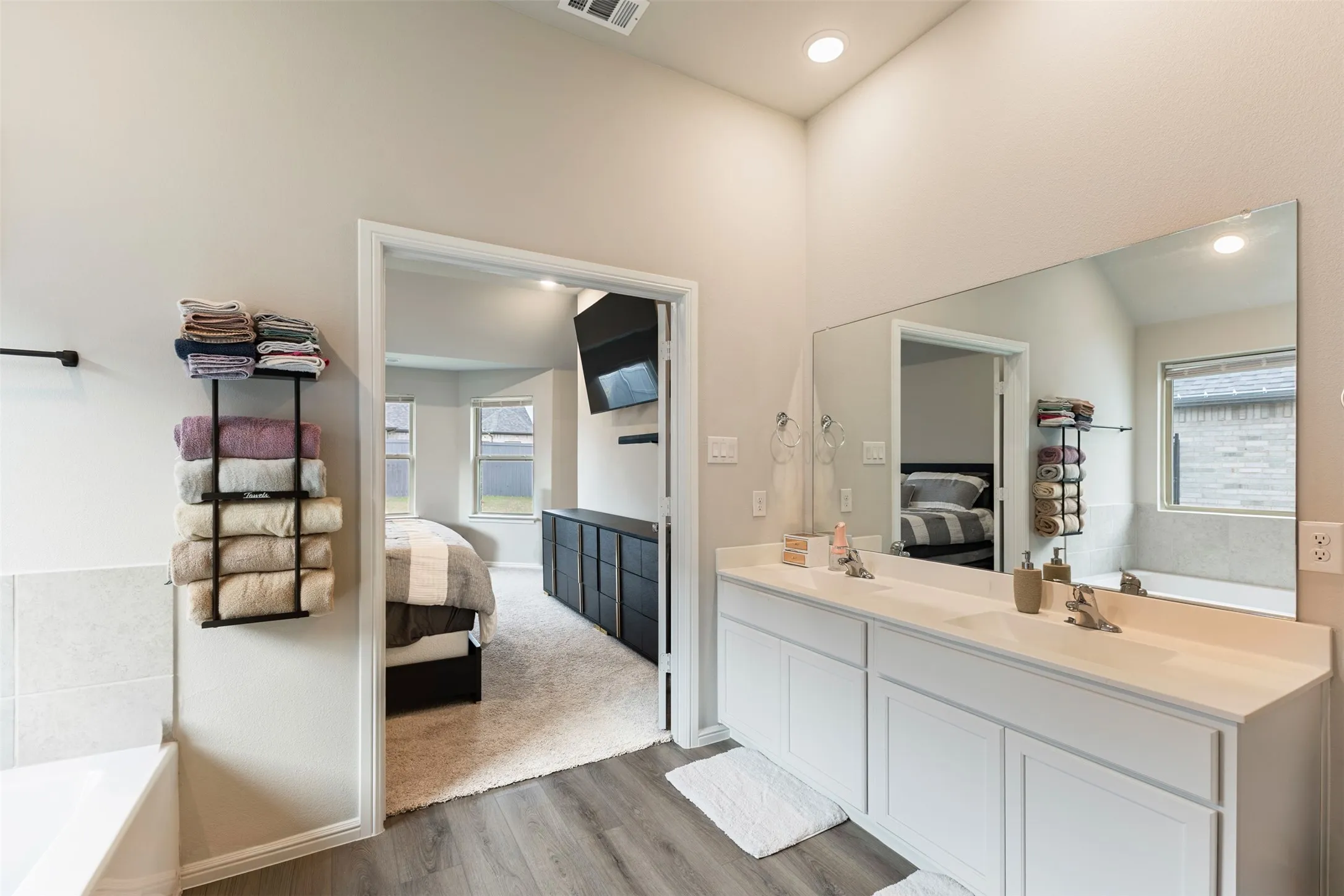 Bathroom featuring ensuite bathroom, a bath, double vanity, and light wood-style floors