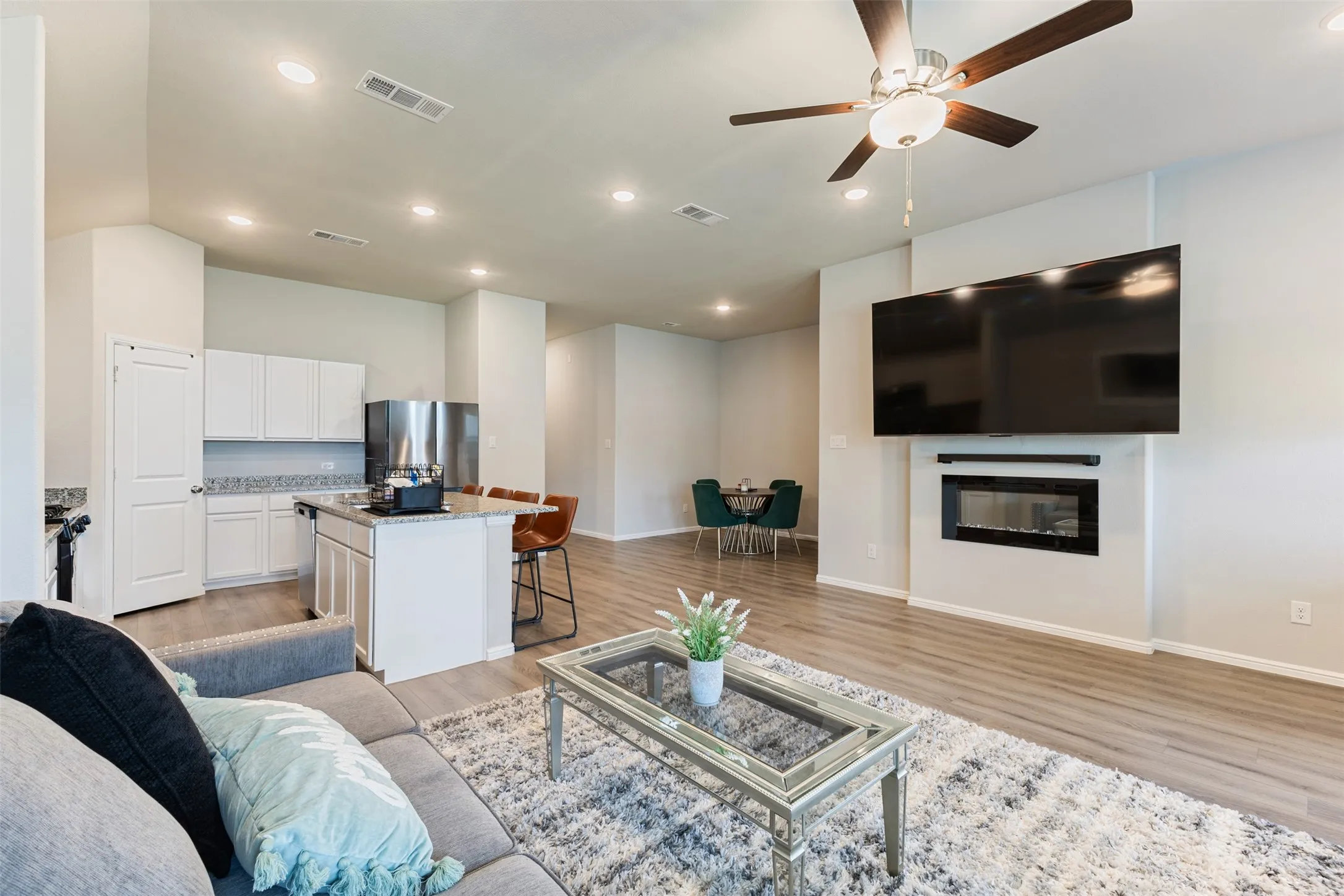 Living area featuring recessed lighting, a ceiling fan, light wood-style flooring, and a glass covered fireplace