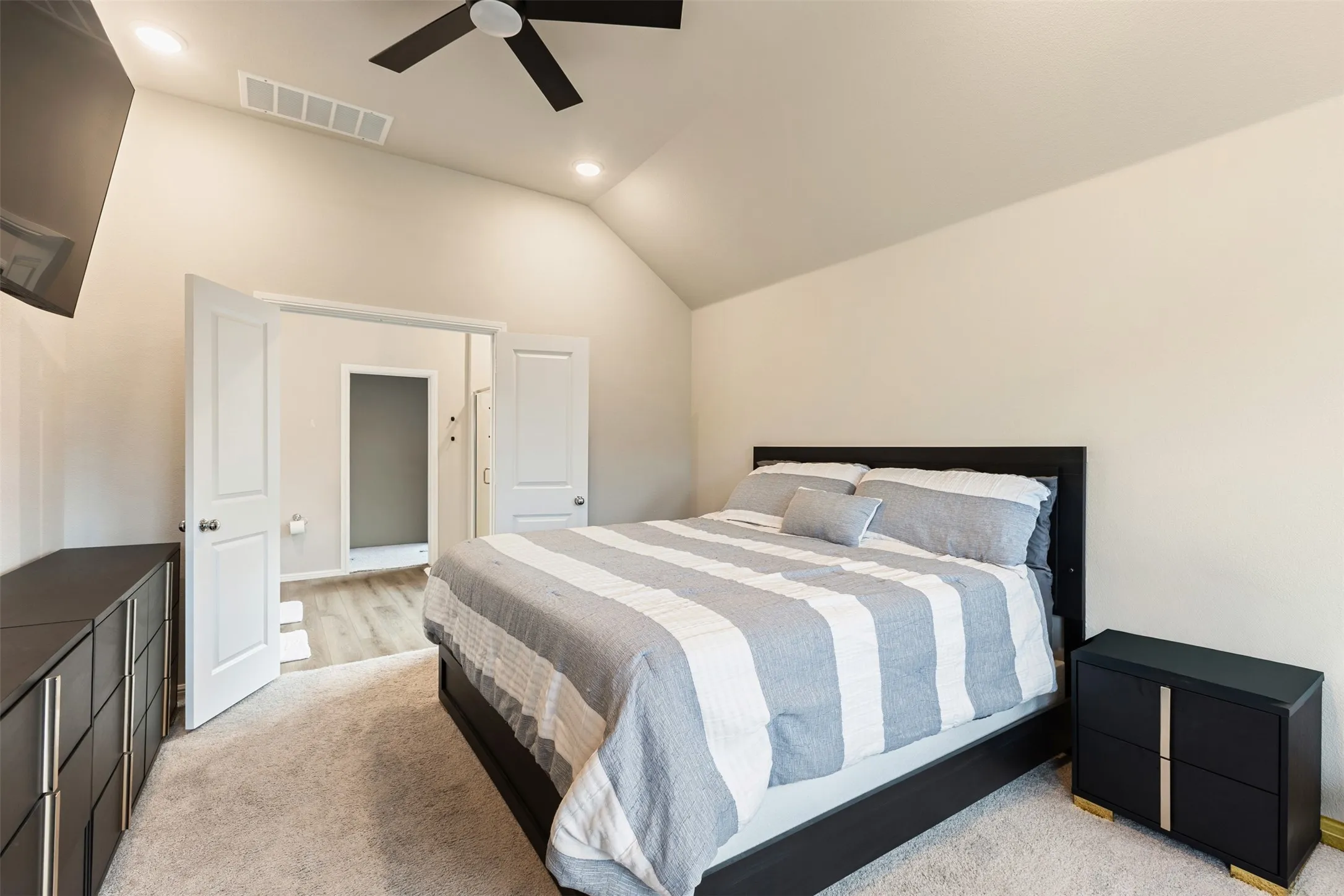 Bedroom with lofted ceiling, recessed lighting, ceiling fan, and light carpet