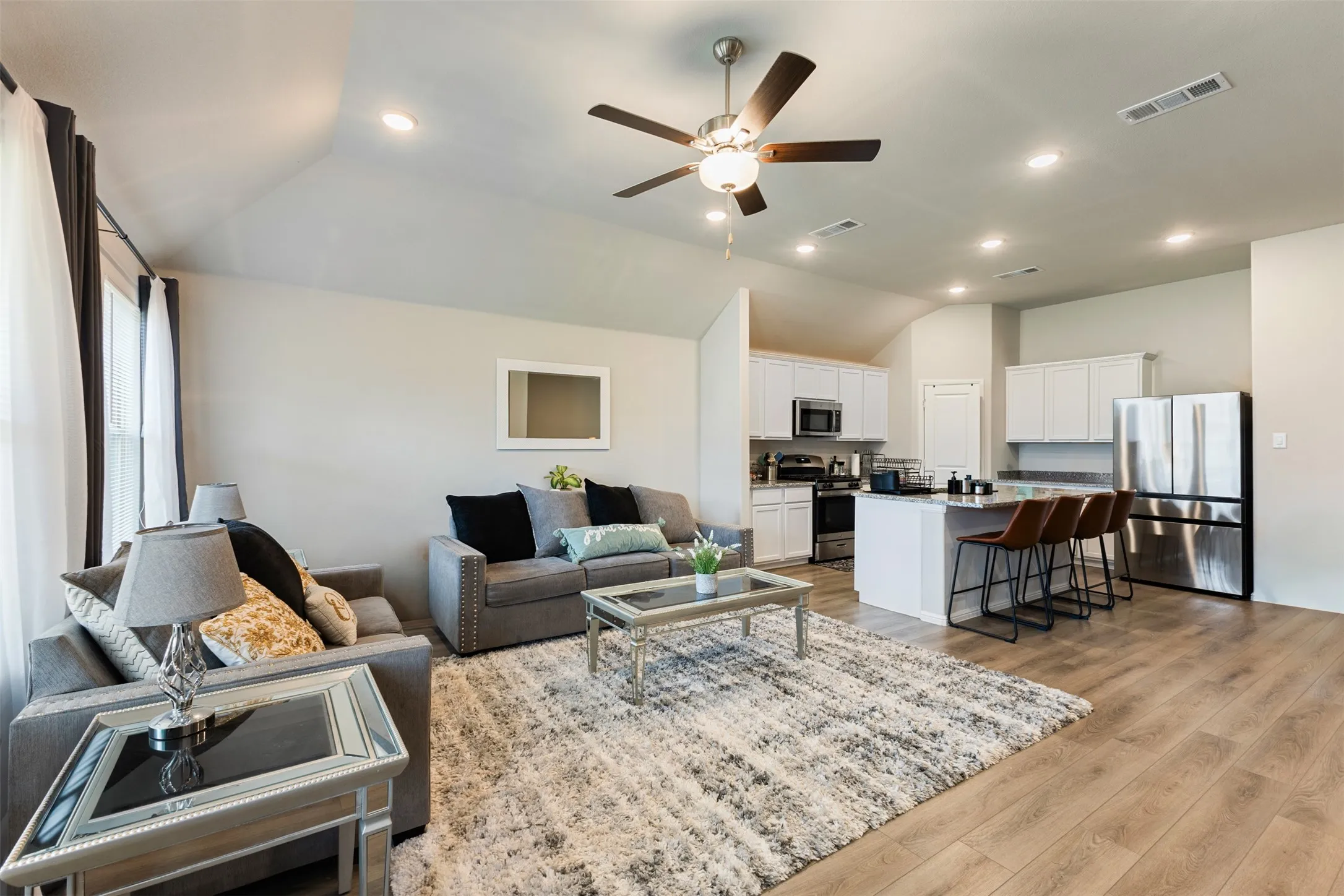 Living room featuring lofted ceiling, recessed lighting, light wood-style flooring, and a ceiling fan