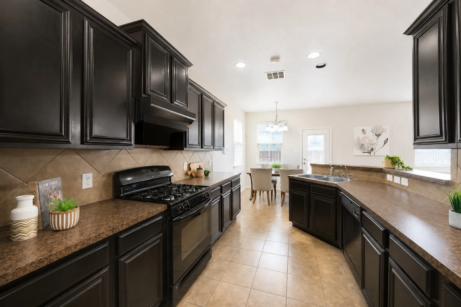 Kitchen featuring dark wood-finish cabinetry, built-in gas range, dual basin sink, and tile flooring
