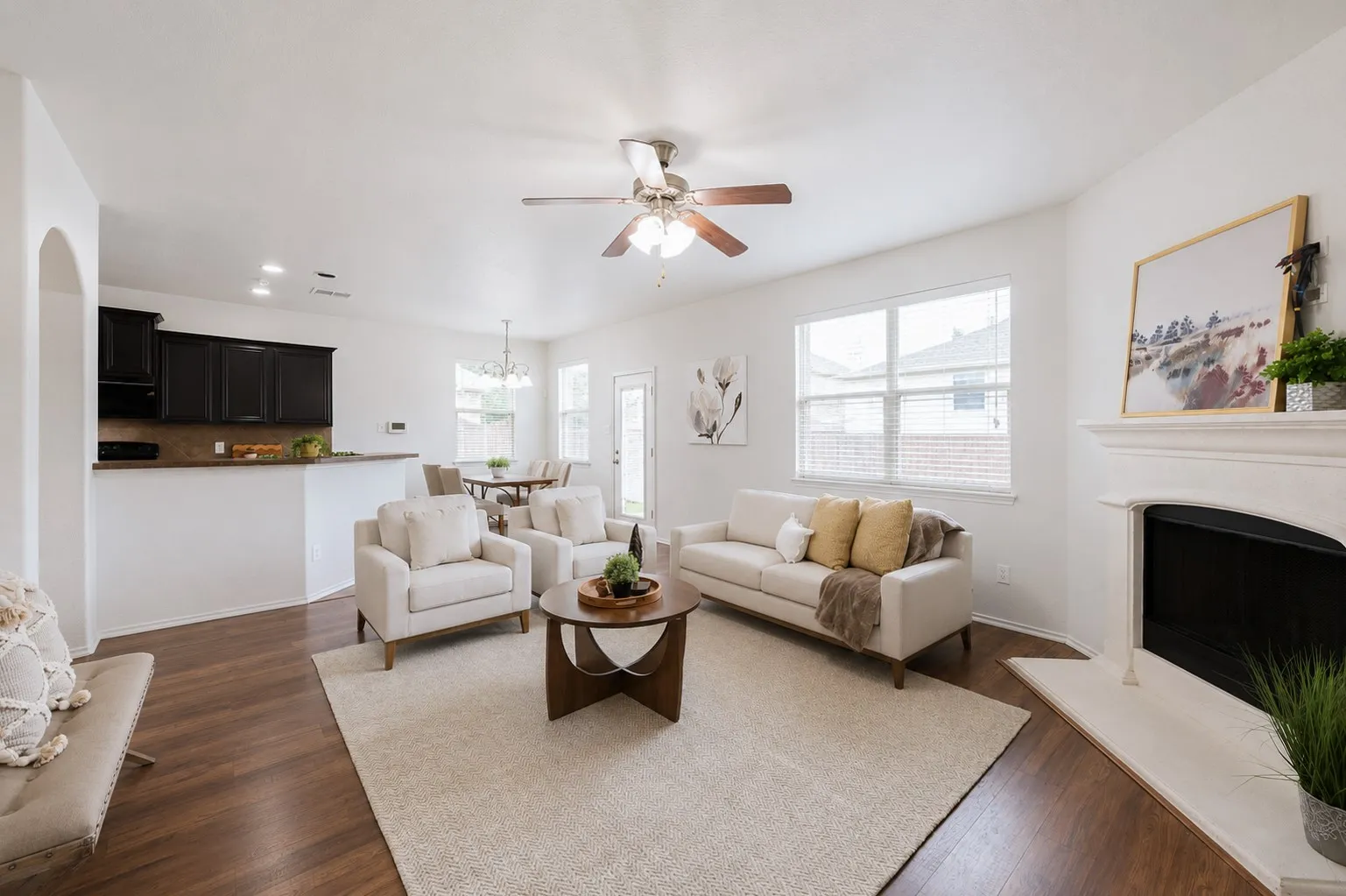 Wood-finish flooring throughout, white walls, and a recessed fireplace with a white mantel