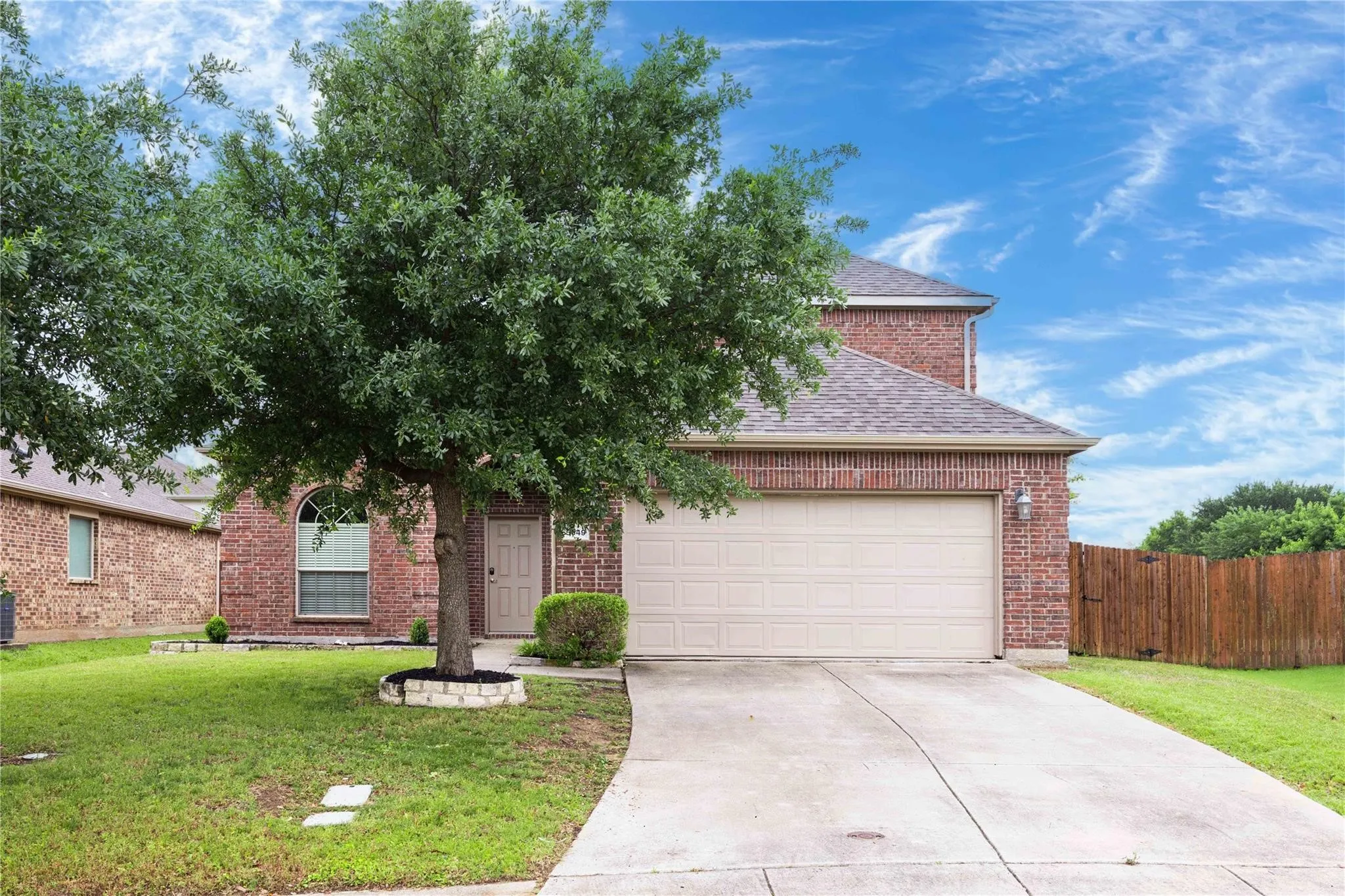 Brick exterior with an arched window, two-car garage, and a concrete driveway