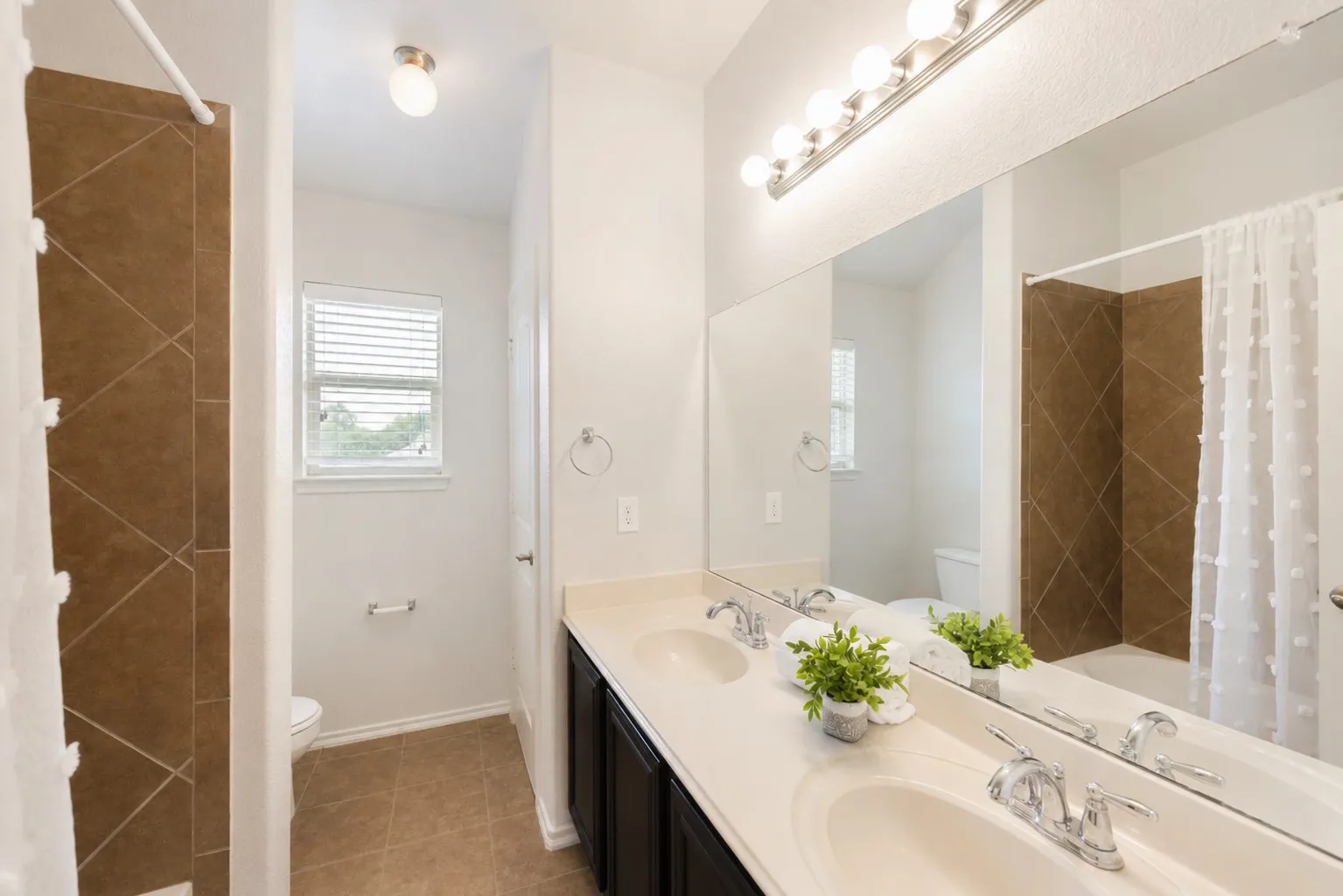 Dual vanity with integrated sinks, expansive mirror, brushed nickel hardware, and overhead bar lighting