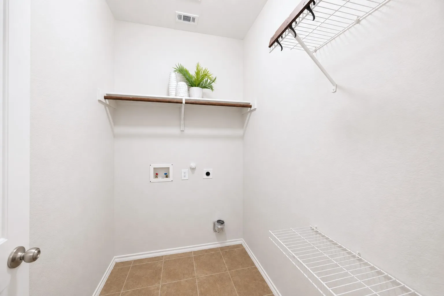 Utility room featuring tile flooring, a wood-finish shelf, and wire shelving