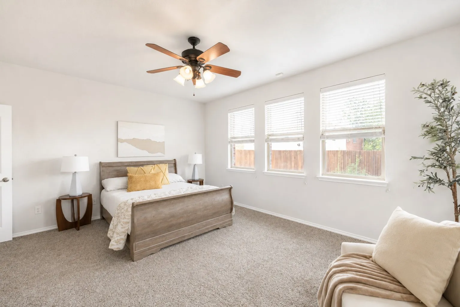 Recessed lighting, ceiling fan with light fixture, three windows with blinds, light-toned carpeting