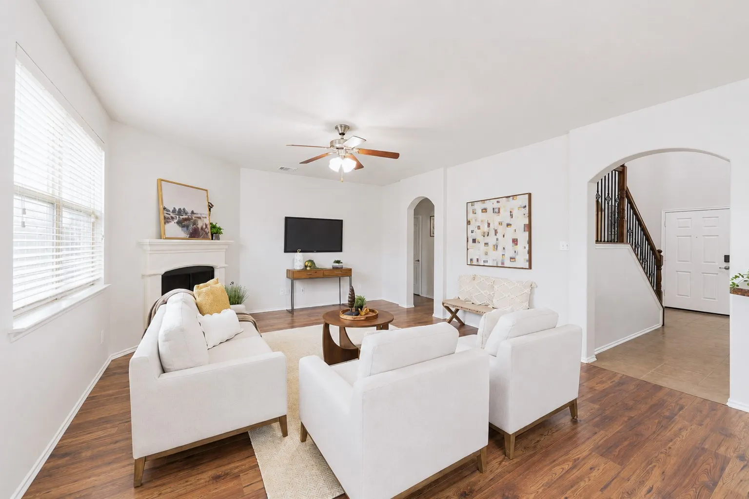 Bright living area featuring wood-finish flooring, a white mantel, and arched doorways