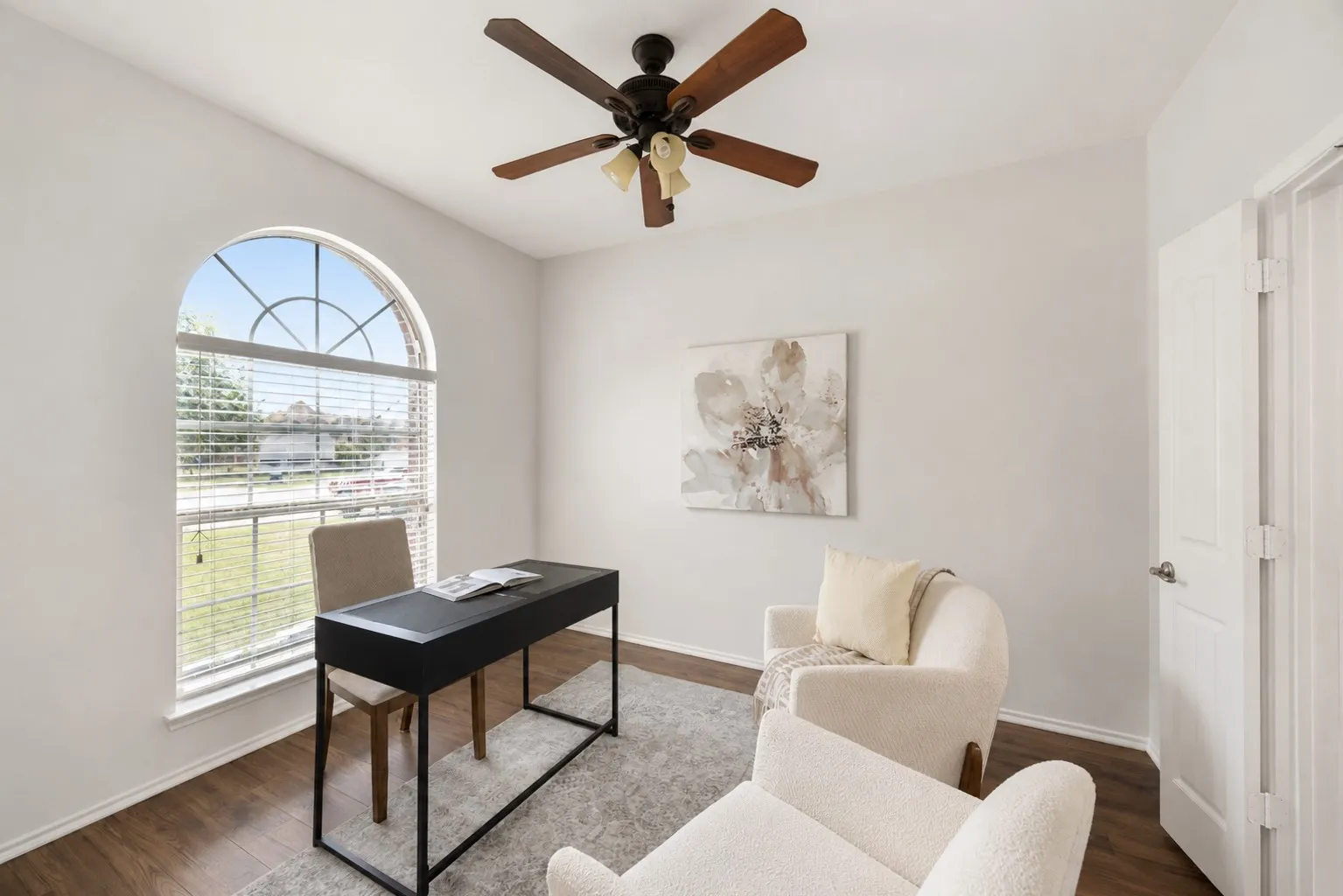 Arched window with gridded upper pane, wood-finish flooring, ceiling fan with integrated lighting, and white paneled door