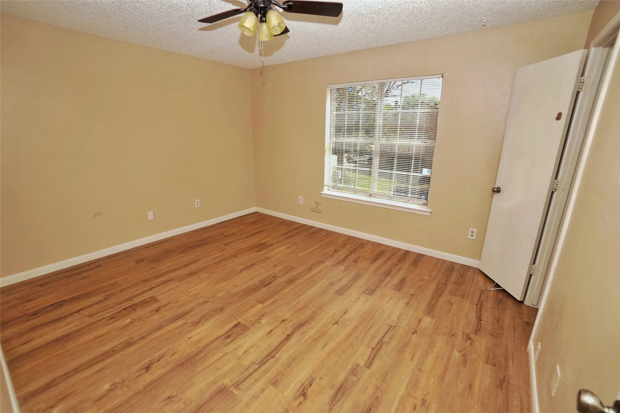 Wood-finish flooring, ceiling fan, and window with exterior scenery
