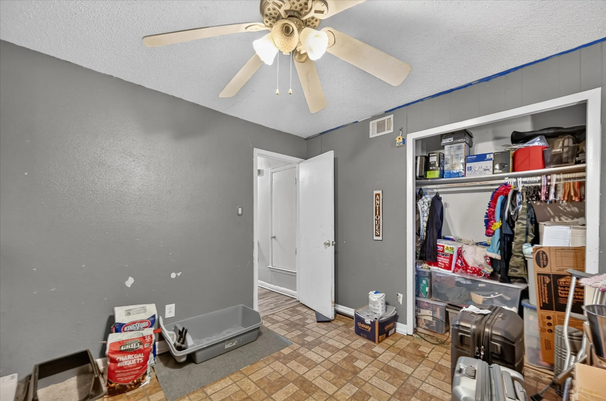 Built-in ceiling fan, textured ceiling, panel accent wall, and a built-in closet with shelving and hanging rod