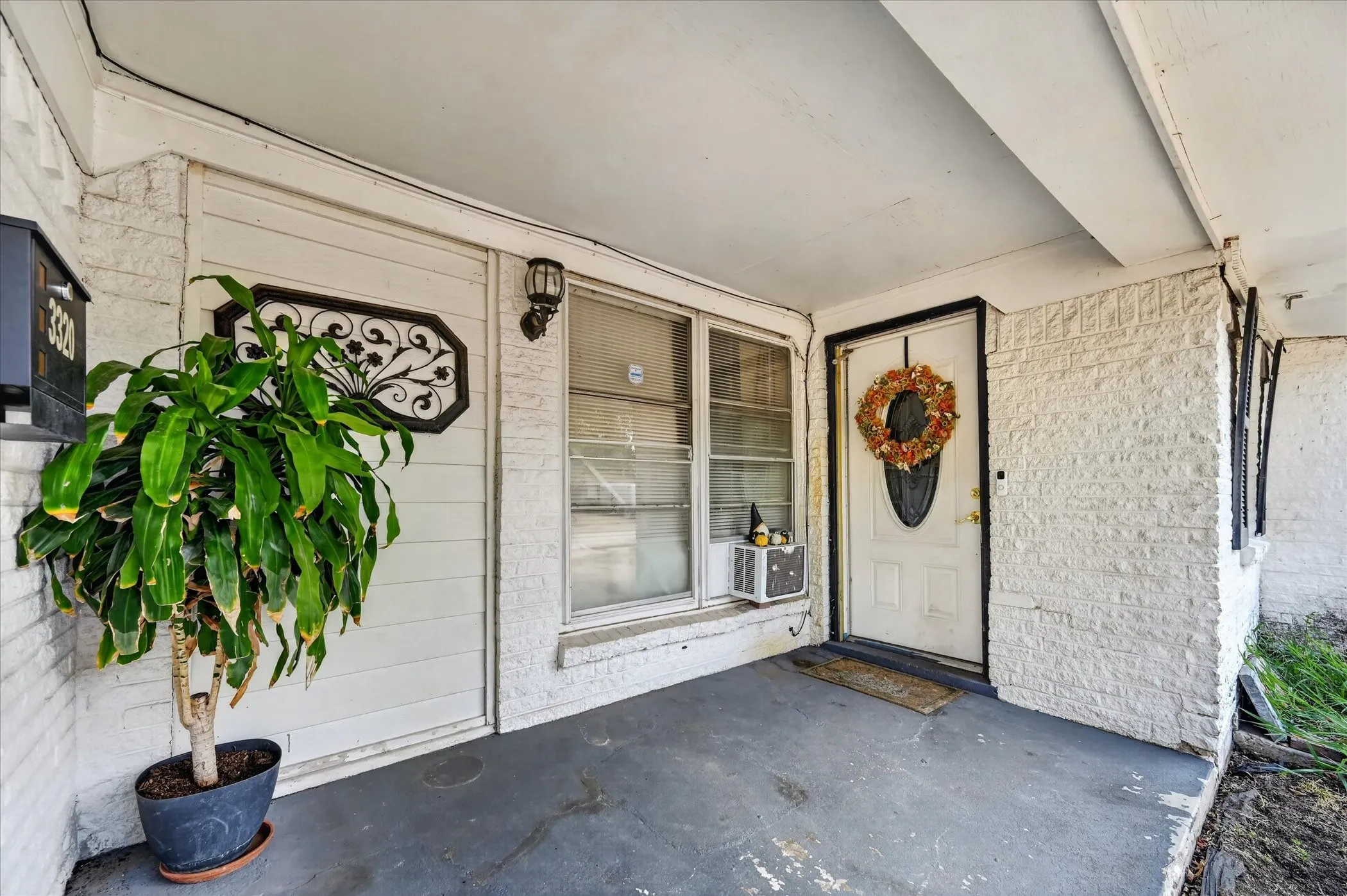 Covered front porch with white painted brick siding and a white entry door