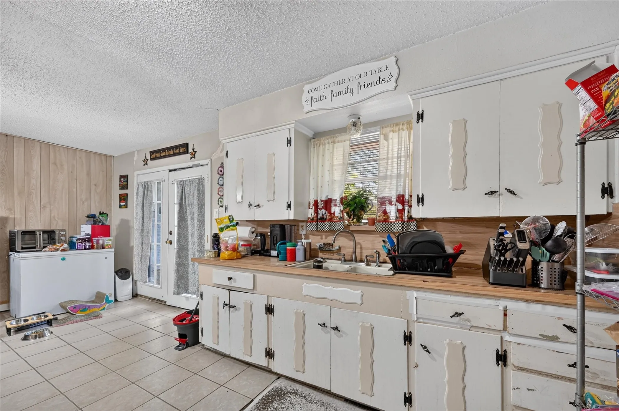 Kitchen with tiled flooring, white cabinetry, wood-finish countertops, and double French doors