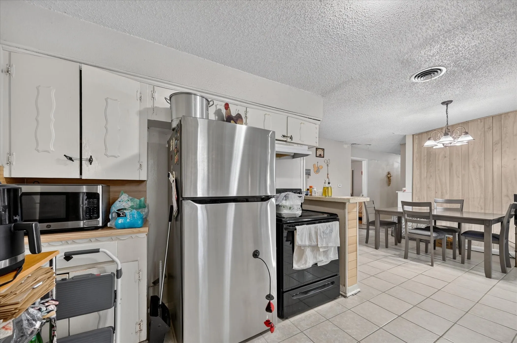 Kitchen featuring white cabinetry, stainless steel appliances, and tile flooring