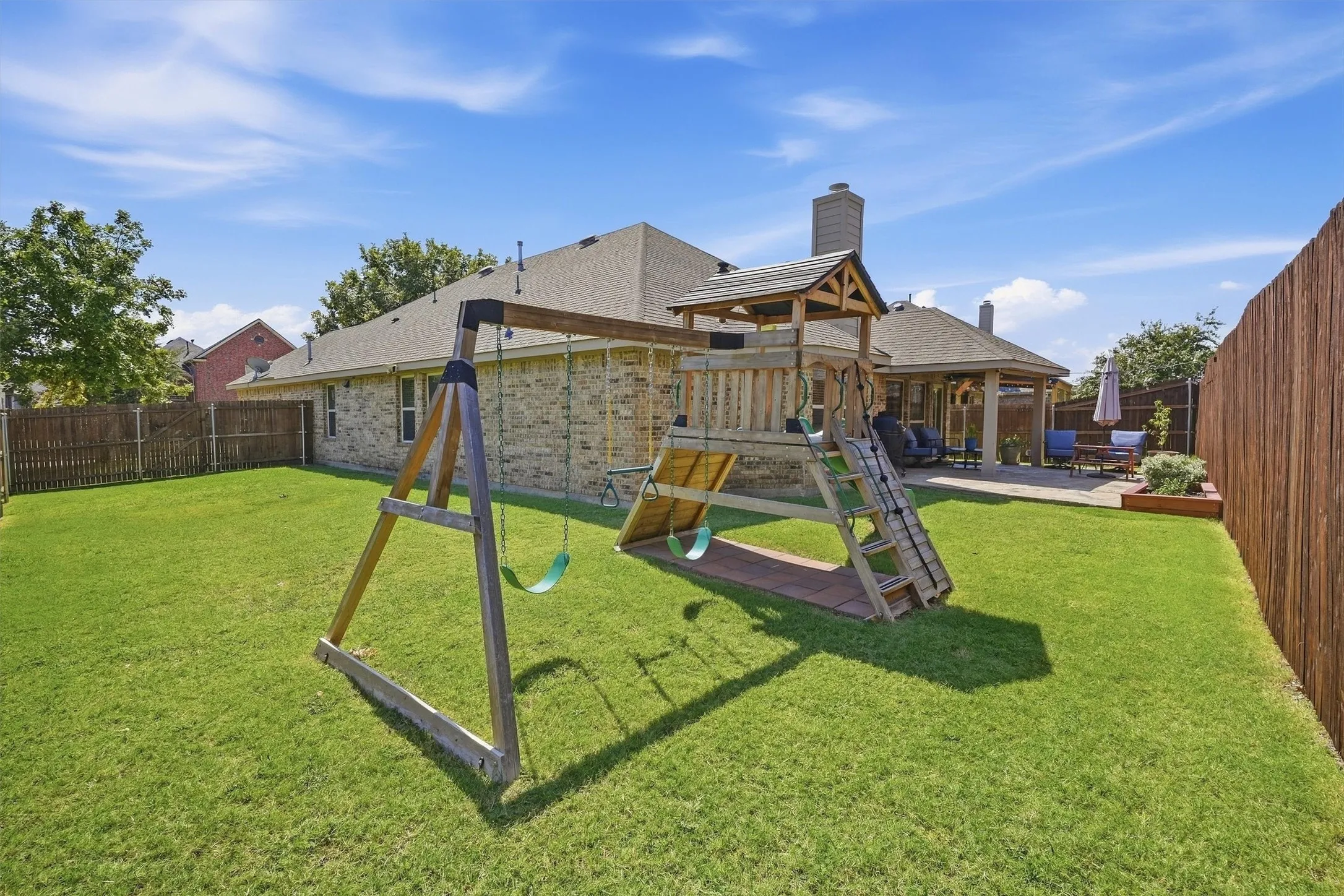 The expansive backyard offers ultimate privacy with its newly raised 8-foot fence on the west side, a lush green lawn, and a wooden playset. Beyond the lawn, a large covered patio creates an ideal setting for hosting outdoor gatherings and entertaining friends.