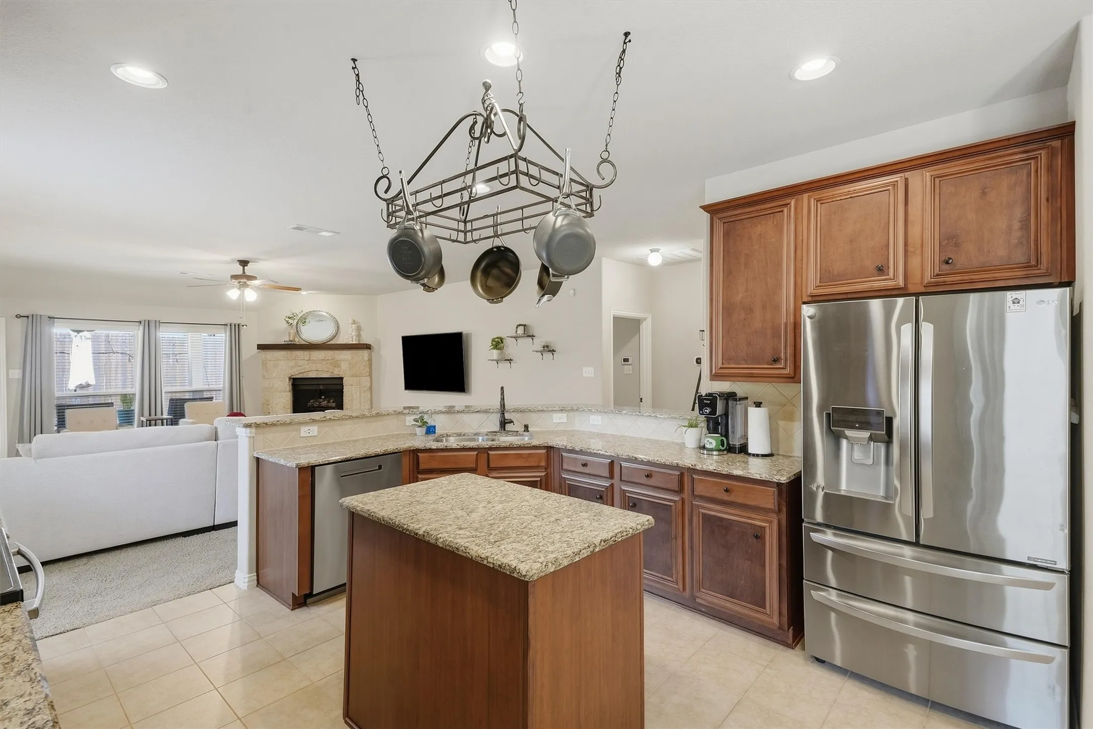 The center island and raised breakfast bar overlooking the main living area. The open floor plan keeps the home cook connected to family and guests around the stone fireplace.