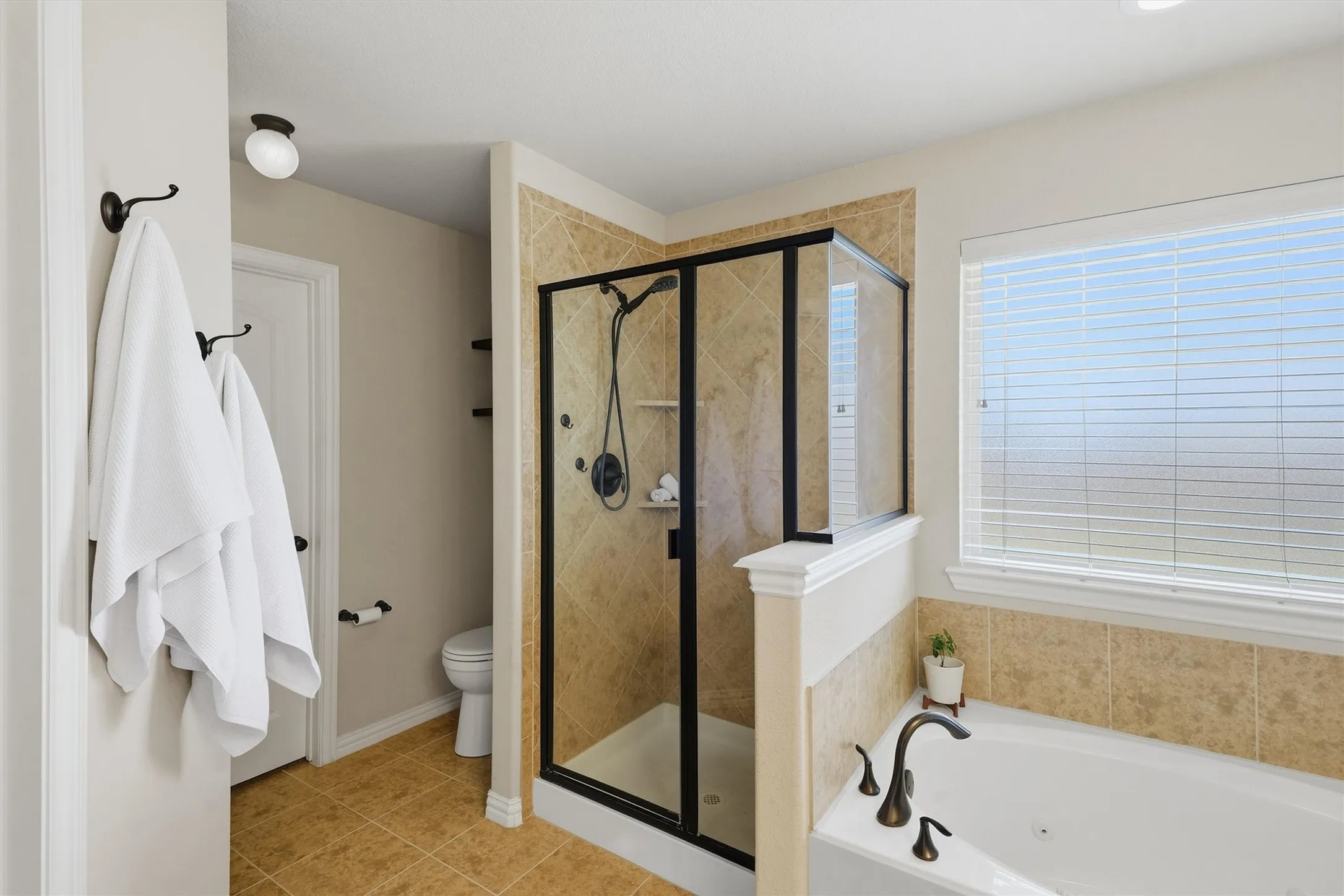 Another great view of the primary bathroom featuring glass enclosed shower, private areato use the restroom, and  walk in closet.