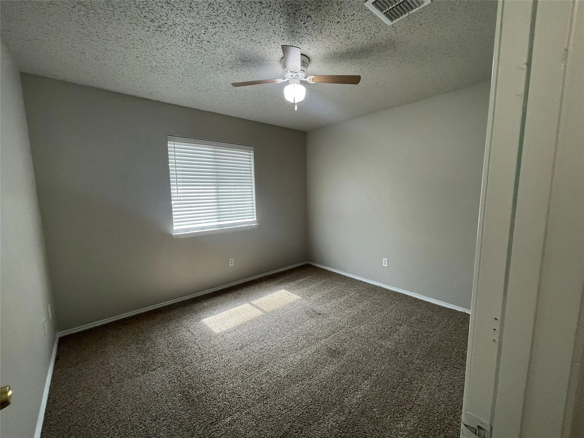 Integrated ceiling fan with light fixture, window with blinds, and textured wall finish