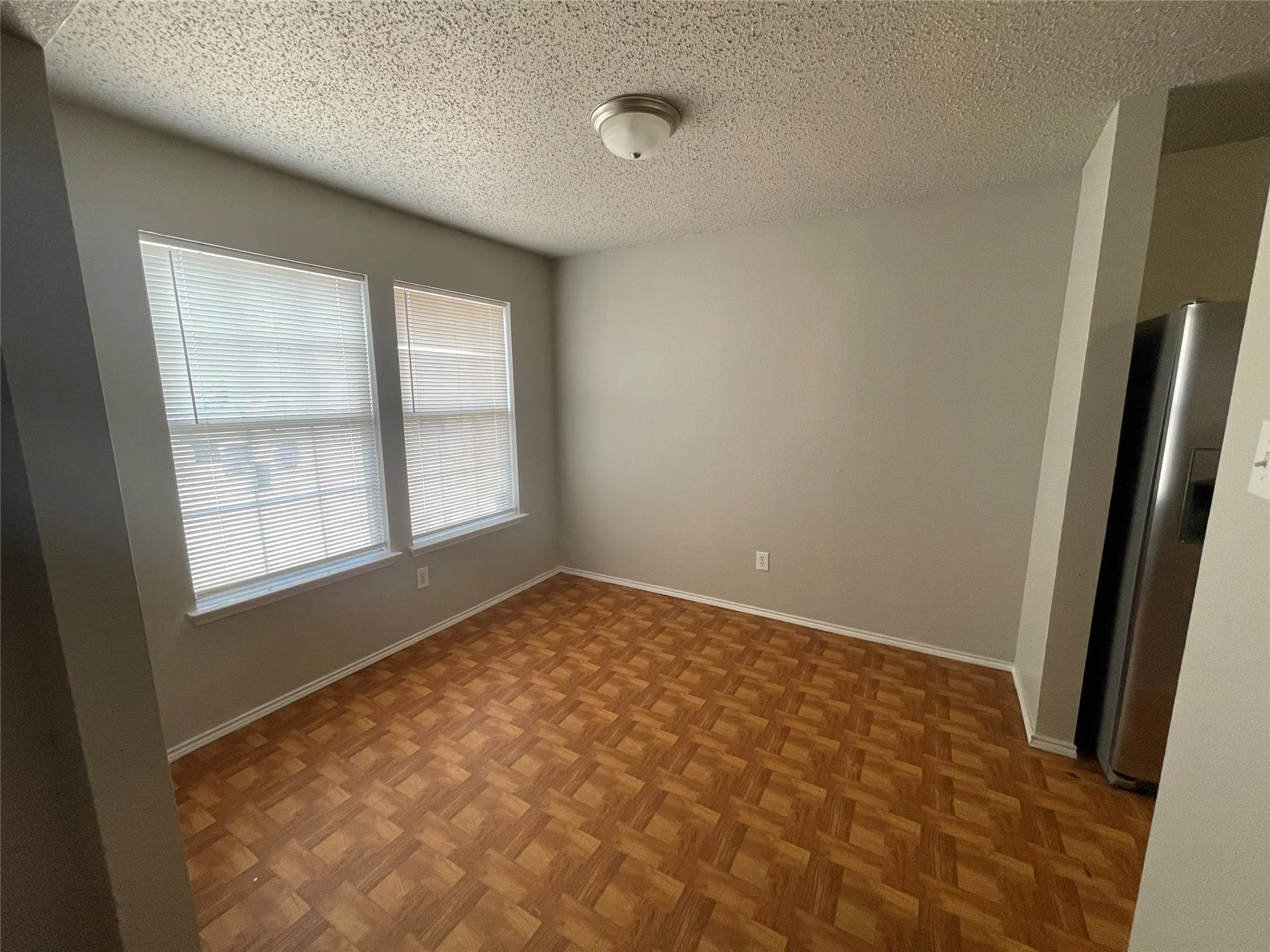Wood-finish flooring, multiple windows with blinds, and a flush mount ceiling light