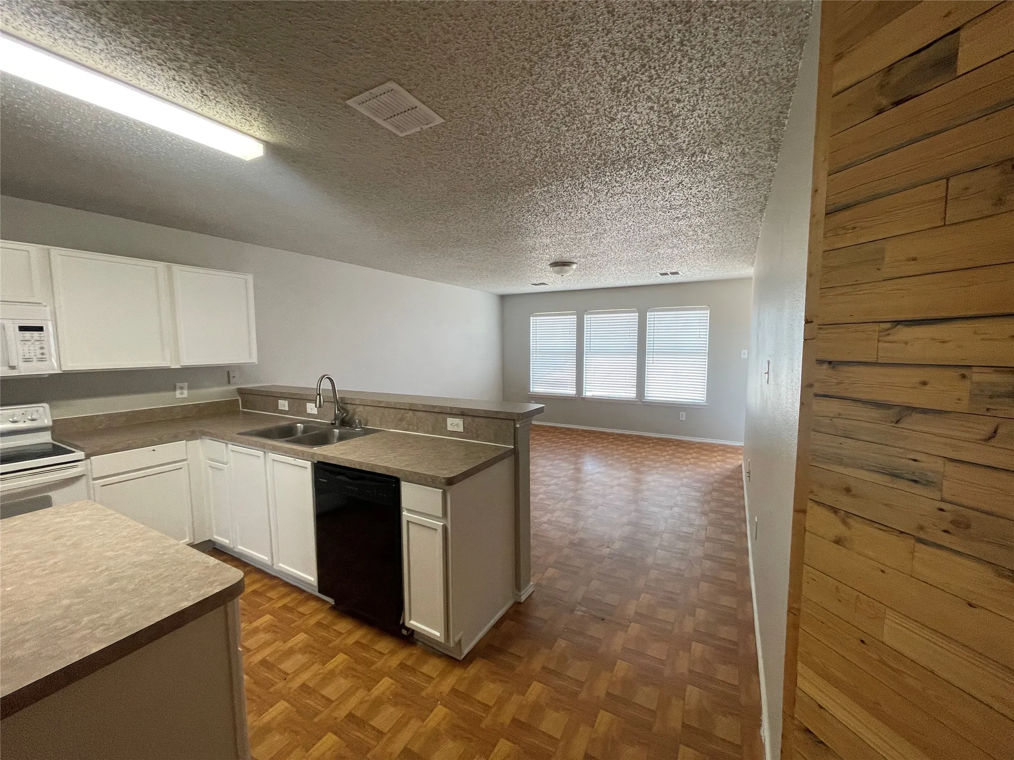 Kitchen with white cabinetry, dual basin sink, and integrated dishwasher