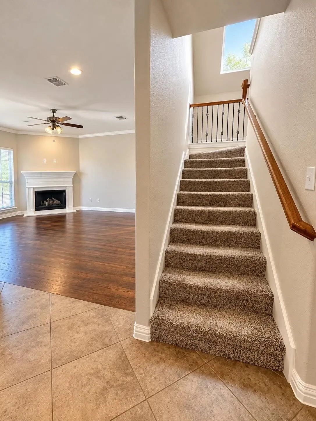 Carpeted staircase with wrought iron balusters and a wood-finish handrail