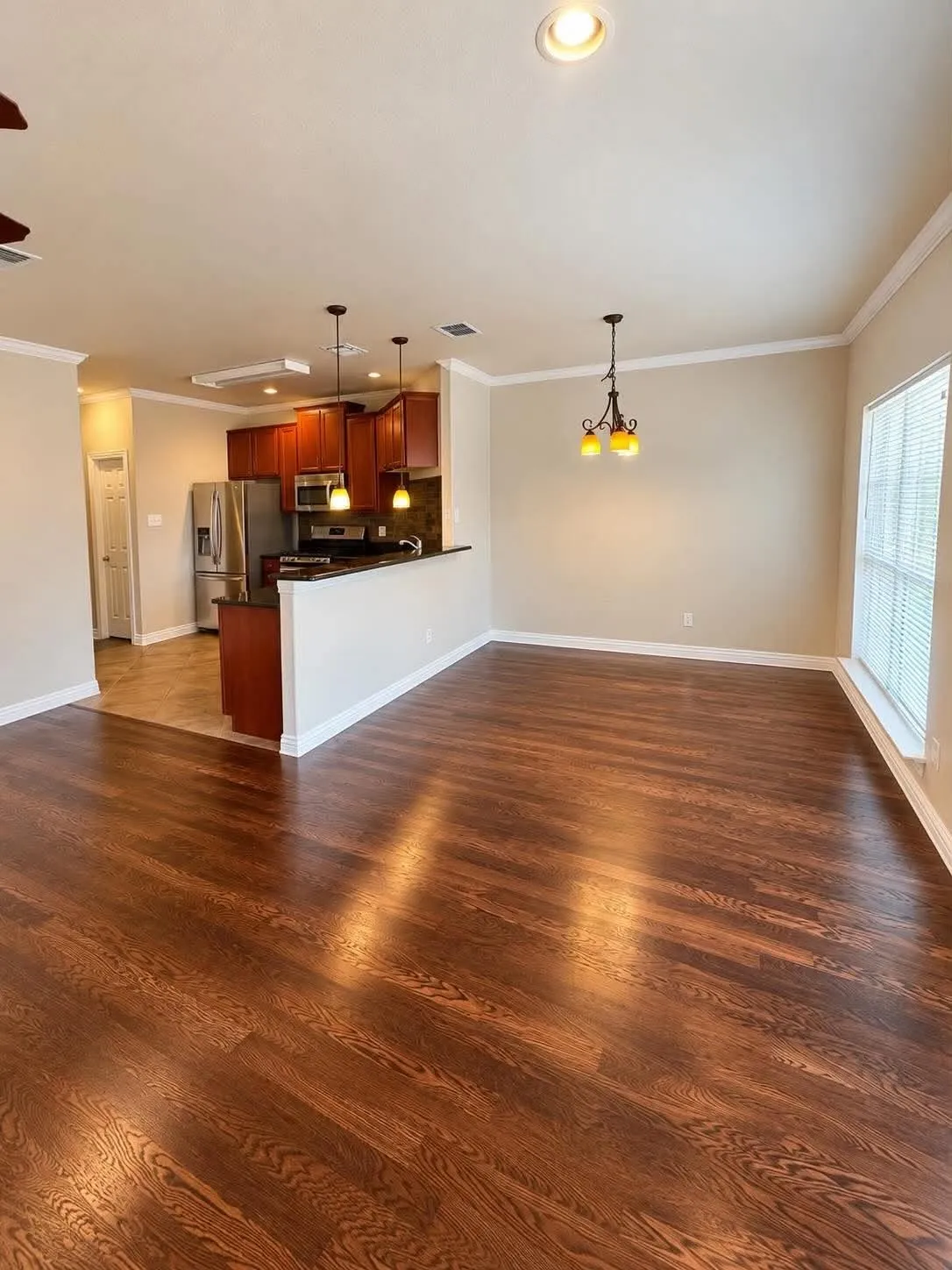 Wood-finish flooring throughout, crown molding, recessed lighting, and kitchen with dark wood cabinetry and stainless steel appliances