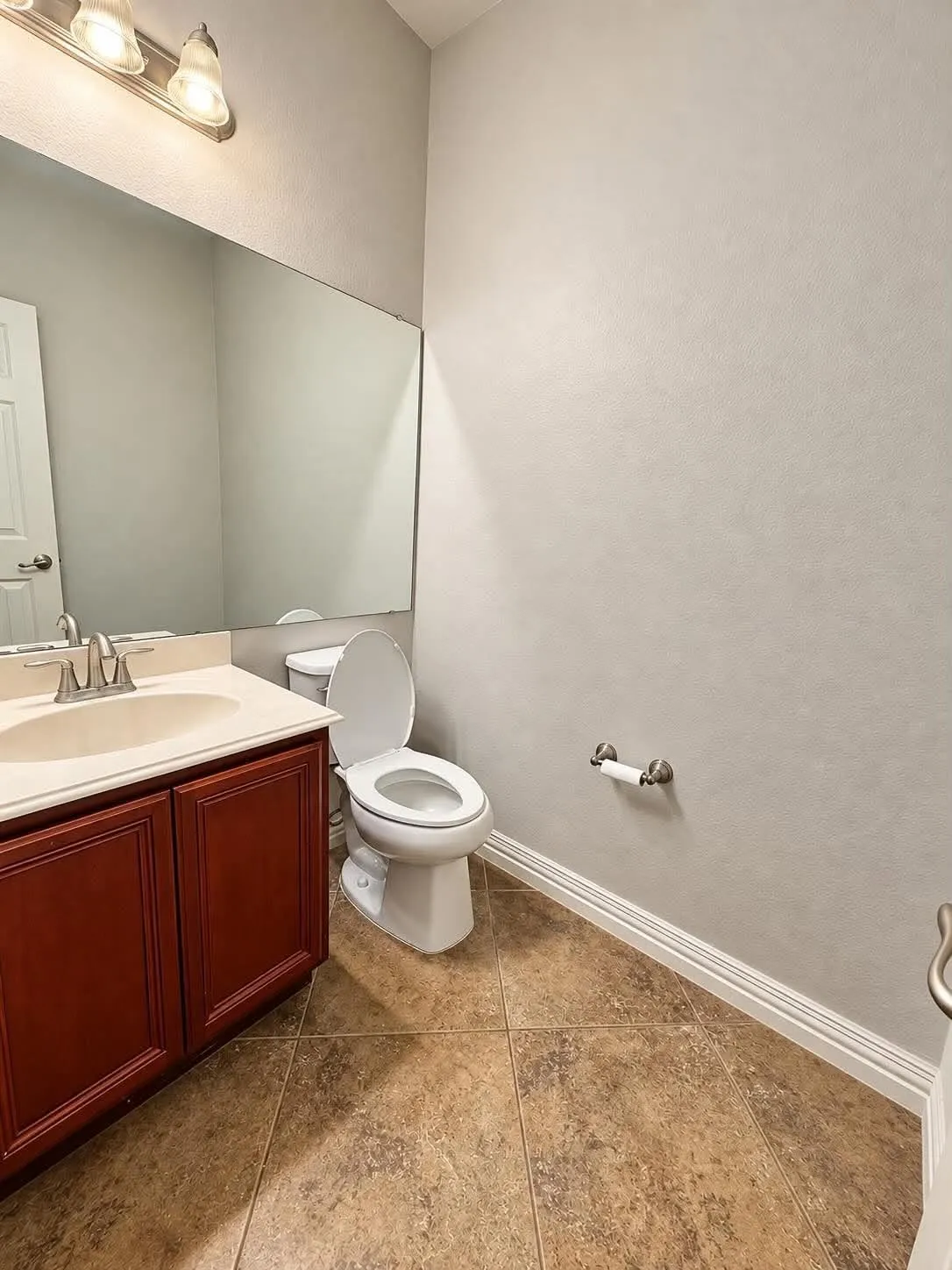 Vanity with wood-finish cabinetry, integrated sink, and brushed nickel faucet