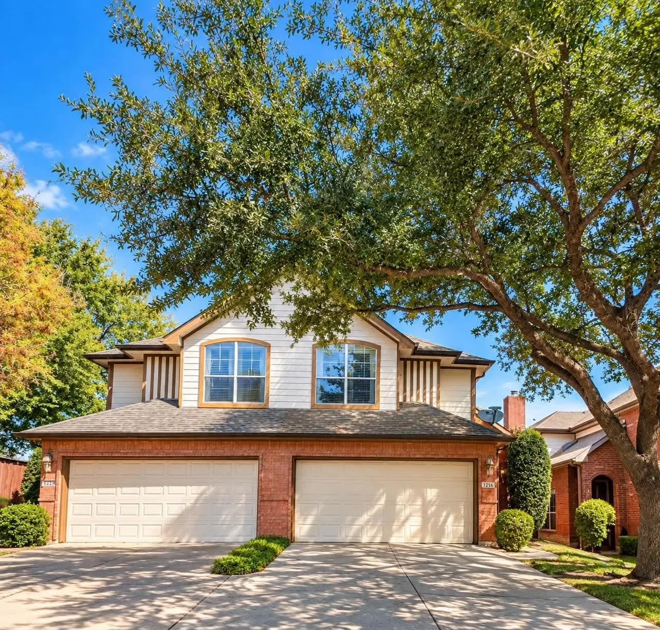 Two-story facade with brick and siding details, arched garage doors, and a double-wide concrete driveway