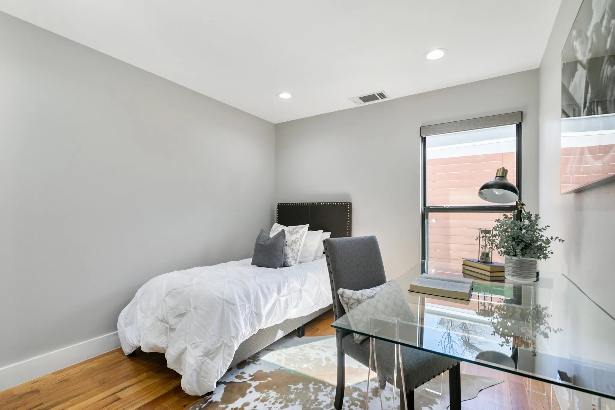 Hardwood flooring, recessed lighting, and a single window with a roller shade