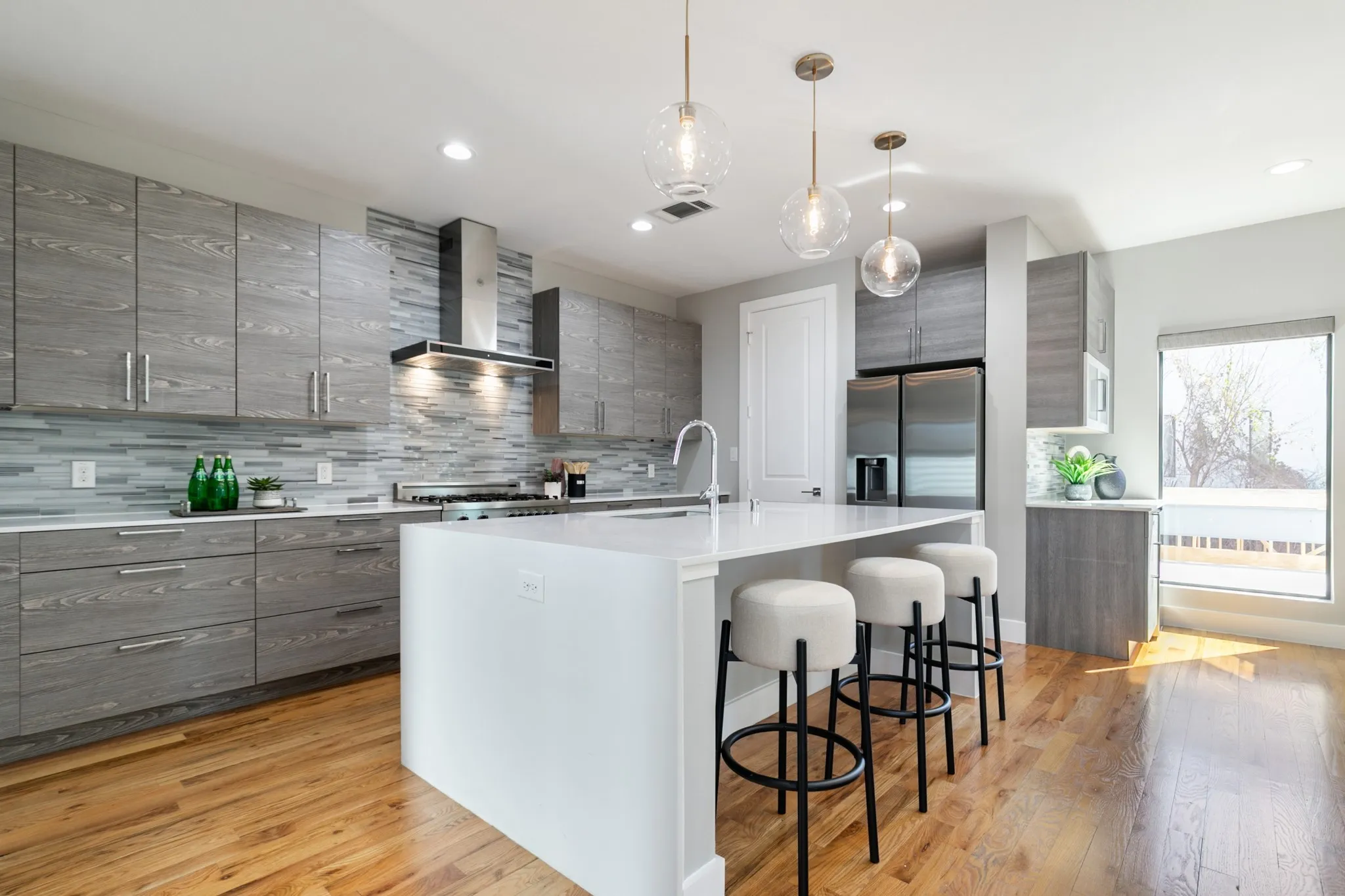 Kitchen featuring wood-finish flooring, a central island with countertop, stainless steel appliances, a tile backsplash, and recessed lighting