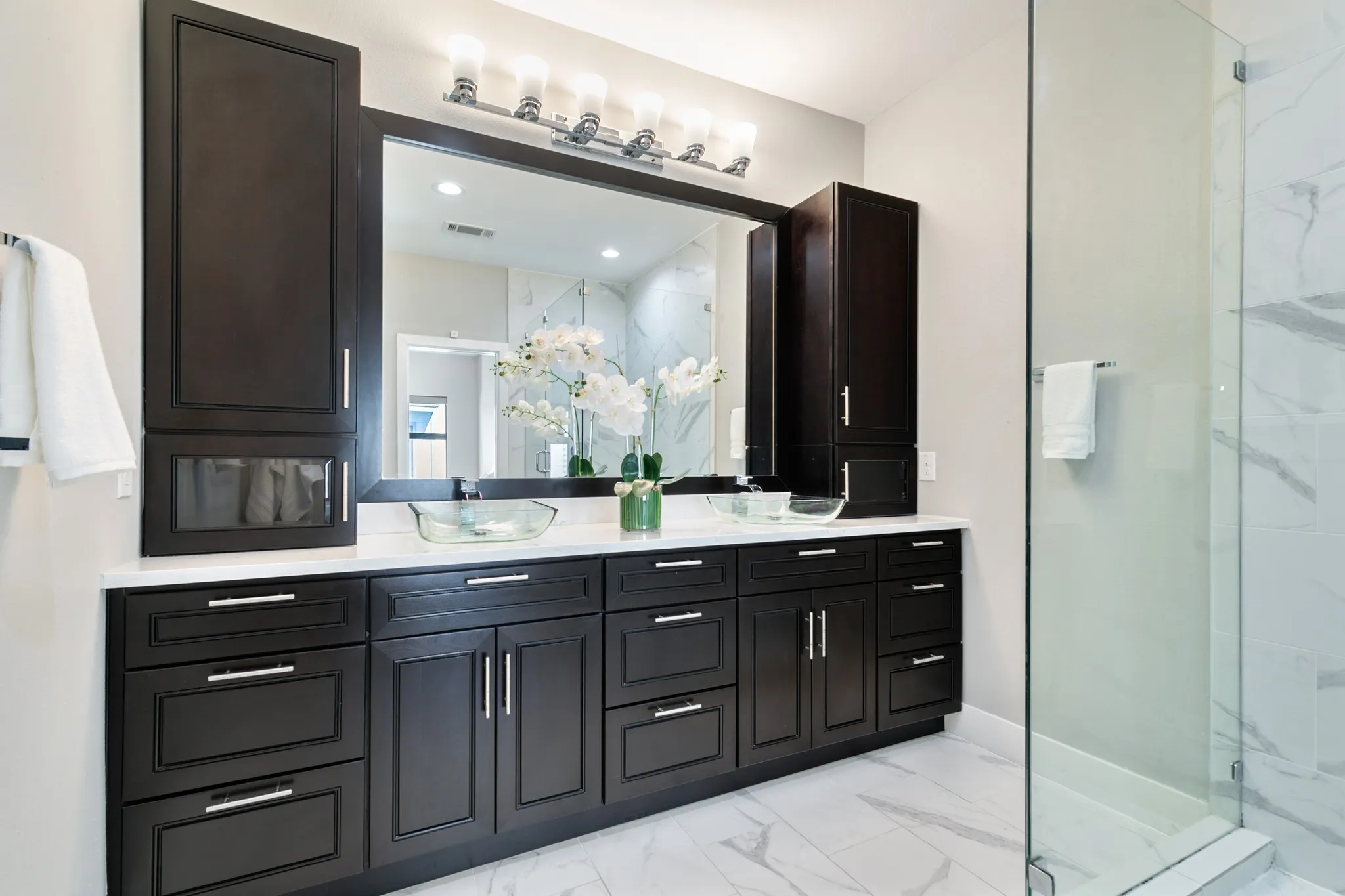 Extended dark wood-finish vanity with dual vessel sinks and ample storage